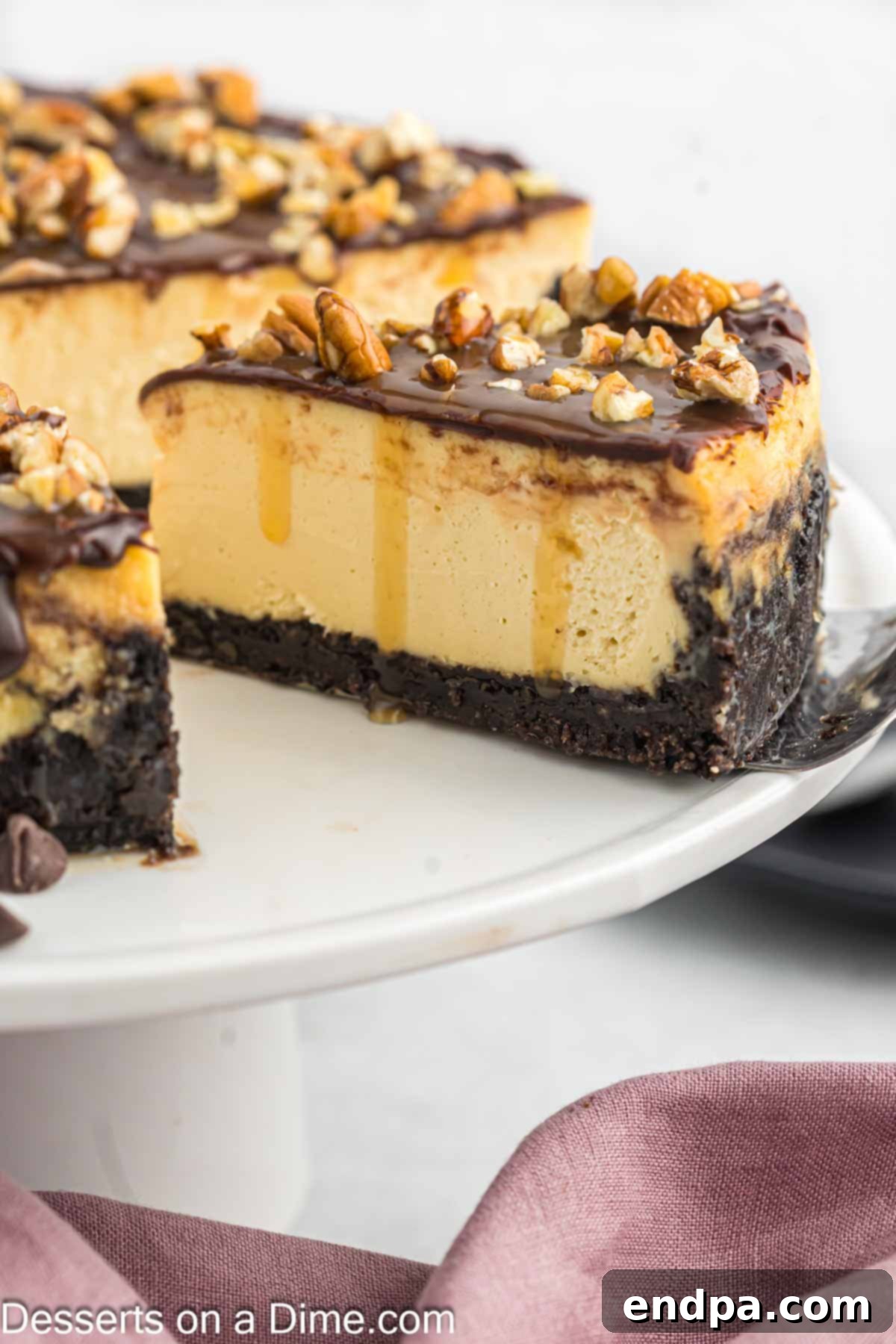 A perfectly sliced Turtle Cheesecake on a white plate, revealing its creamy layers and rich toppings of chocolate, caramel, and pecans.