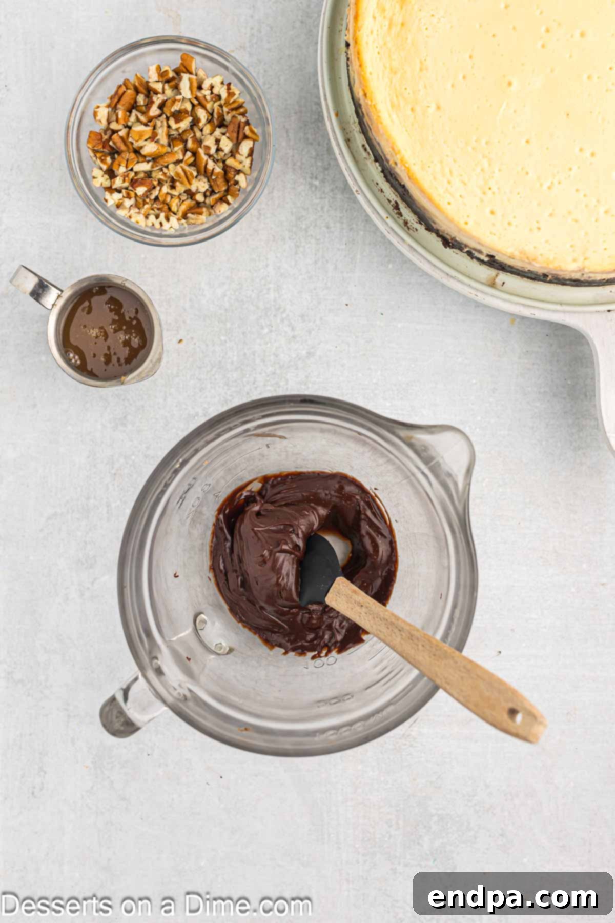 Melted chocolate mixture in a measuring cup, ready to be drizzled over the cheesecake.