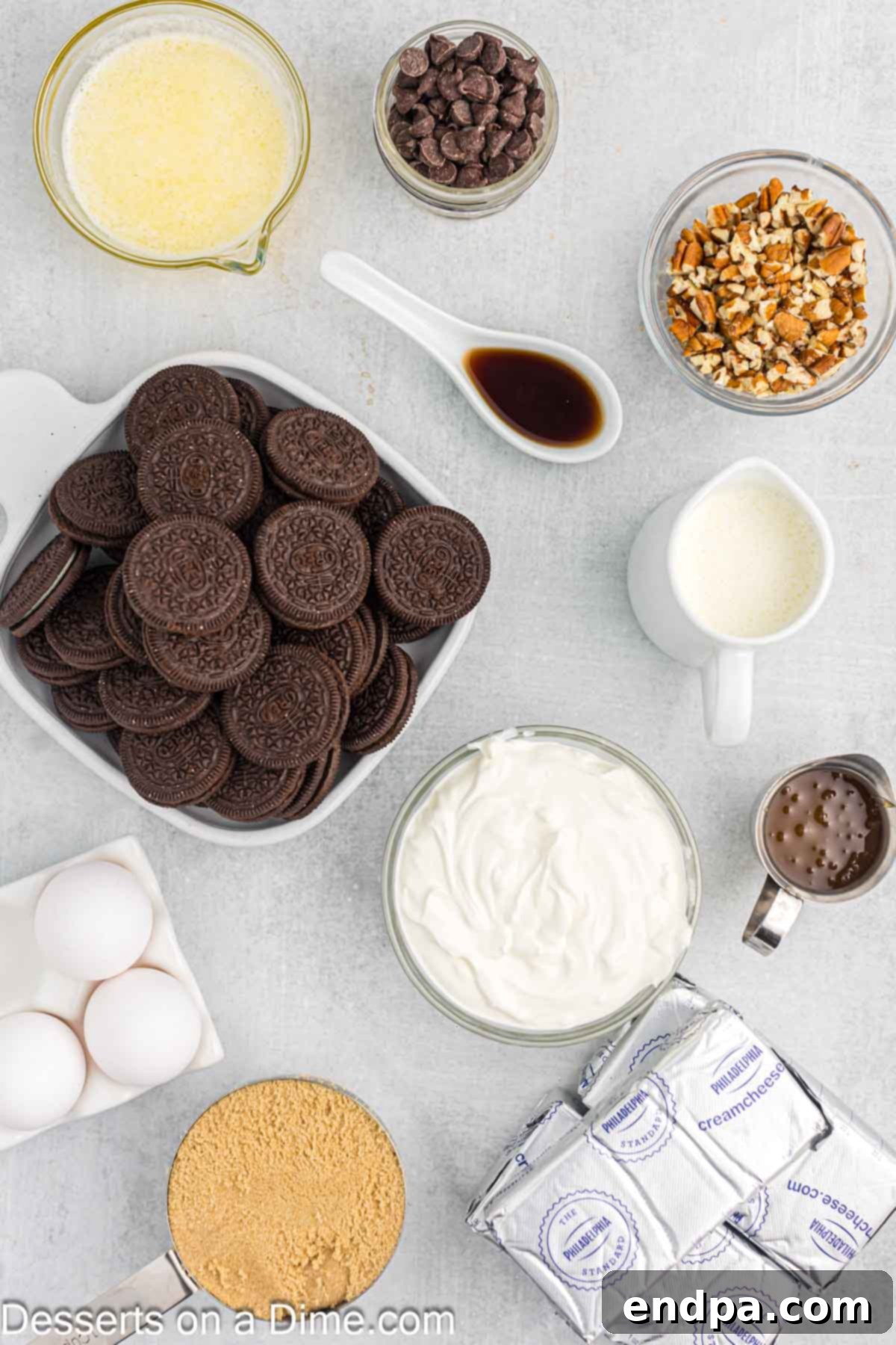 All the fresh ingredients laid out for making Turtle Cheesecake: Oreo cookies, butter, cream cheese, brown sugar, vanilla extract, sour cream, eggs, and heavy cream.