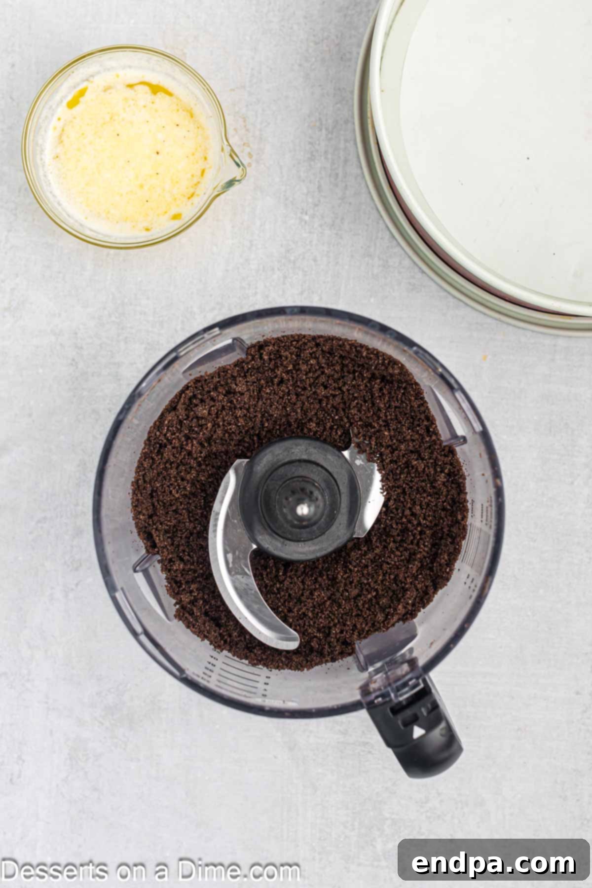 Oreo cookies being crushed in a food processor to make the cheesecake crust.