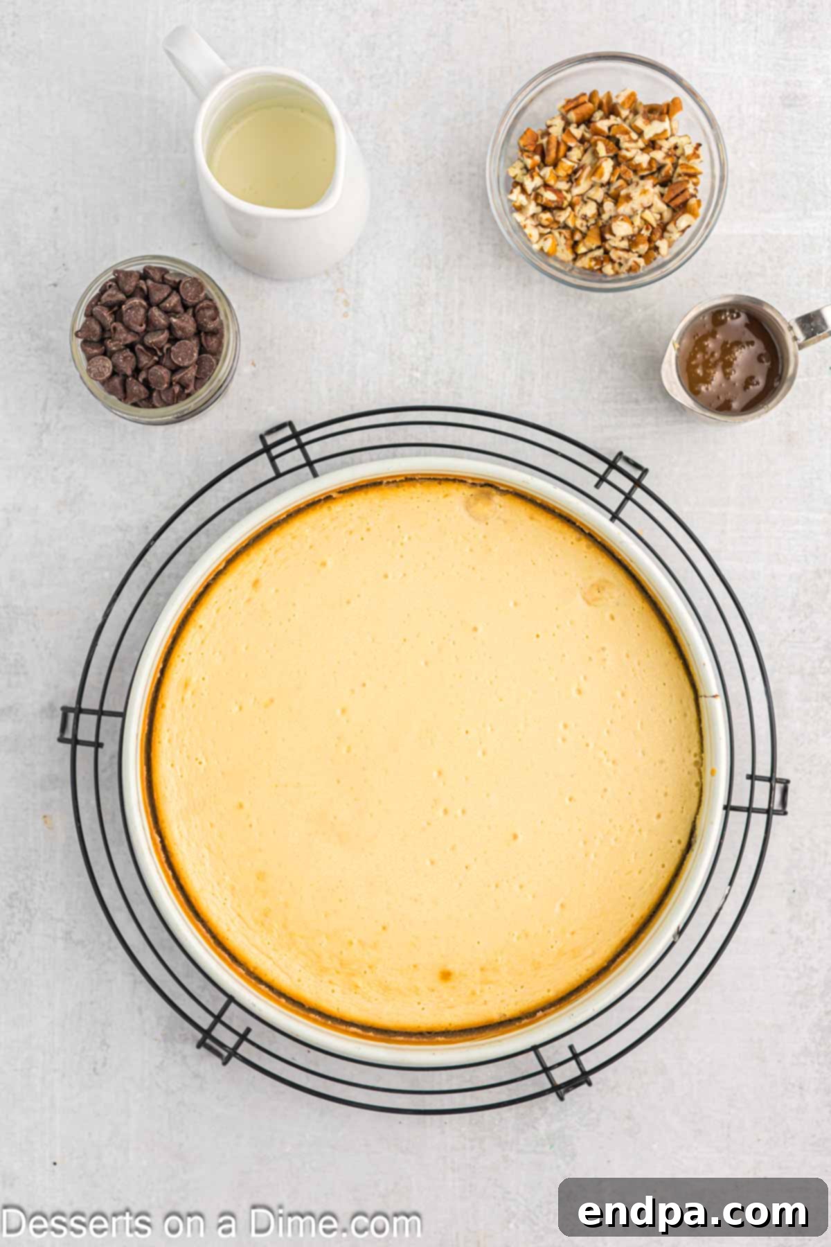 A freshly baked Turtle Cheesecake cooling on a wire rack after being removed from the oven.