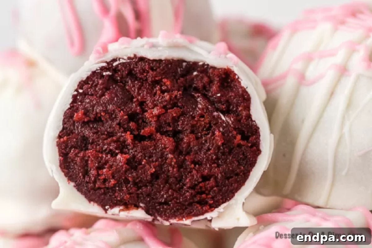 Close-up of a beautifully decorated Red Velvet Cake Ball, showcasing its smooth white chocolate coating and pink drizzle.