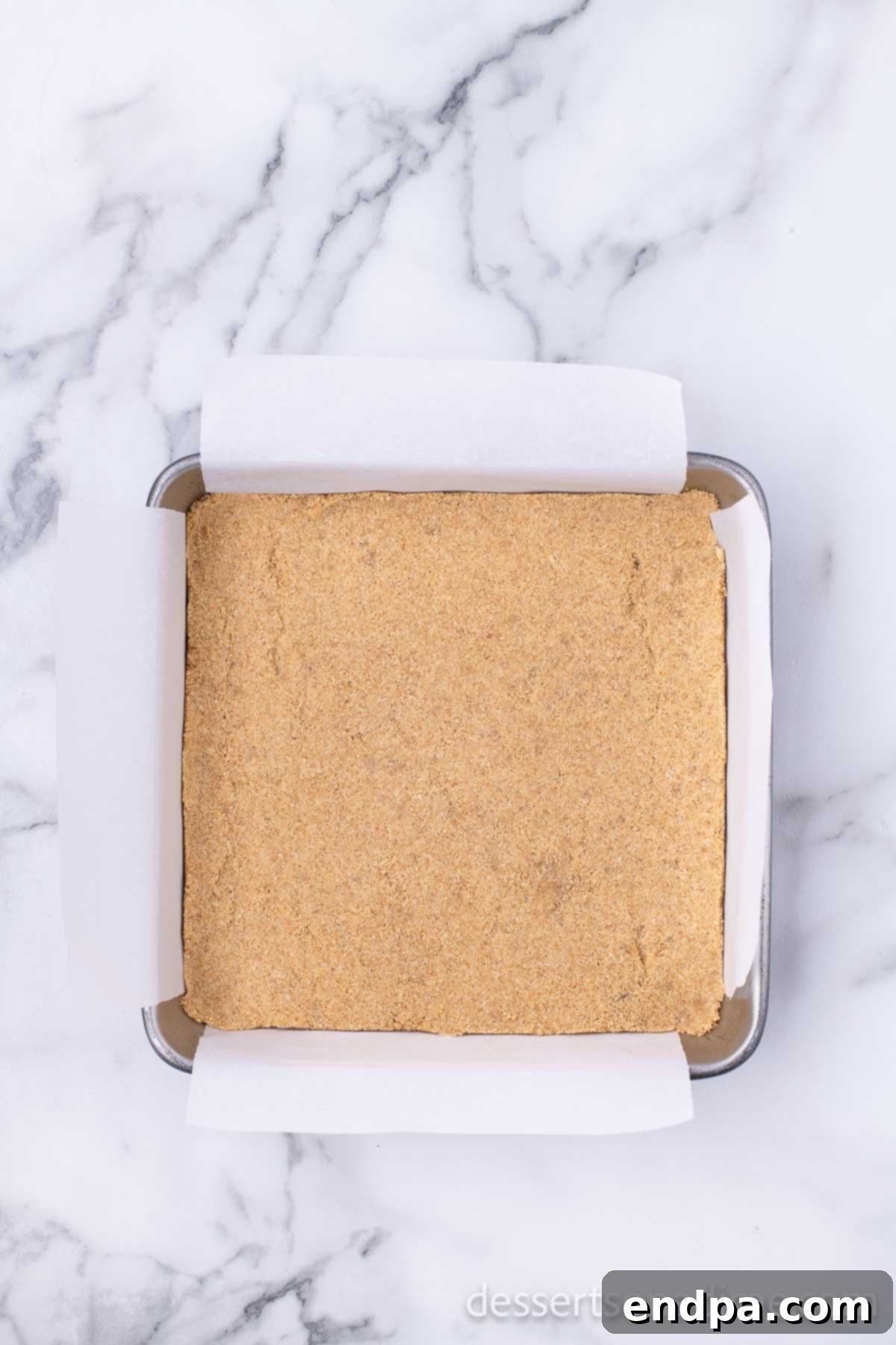 Creamy Cheesecake Delights 5 The graham cracker crust mixture pressed firmly into the bottom of a square baking pan.