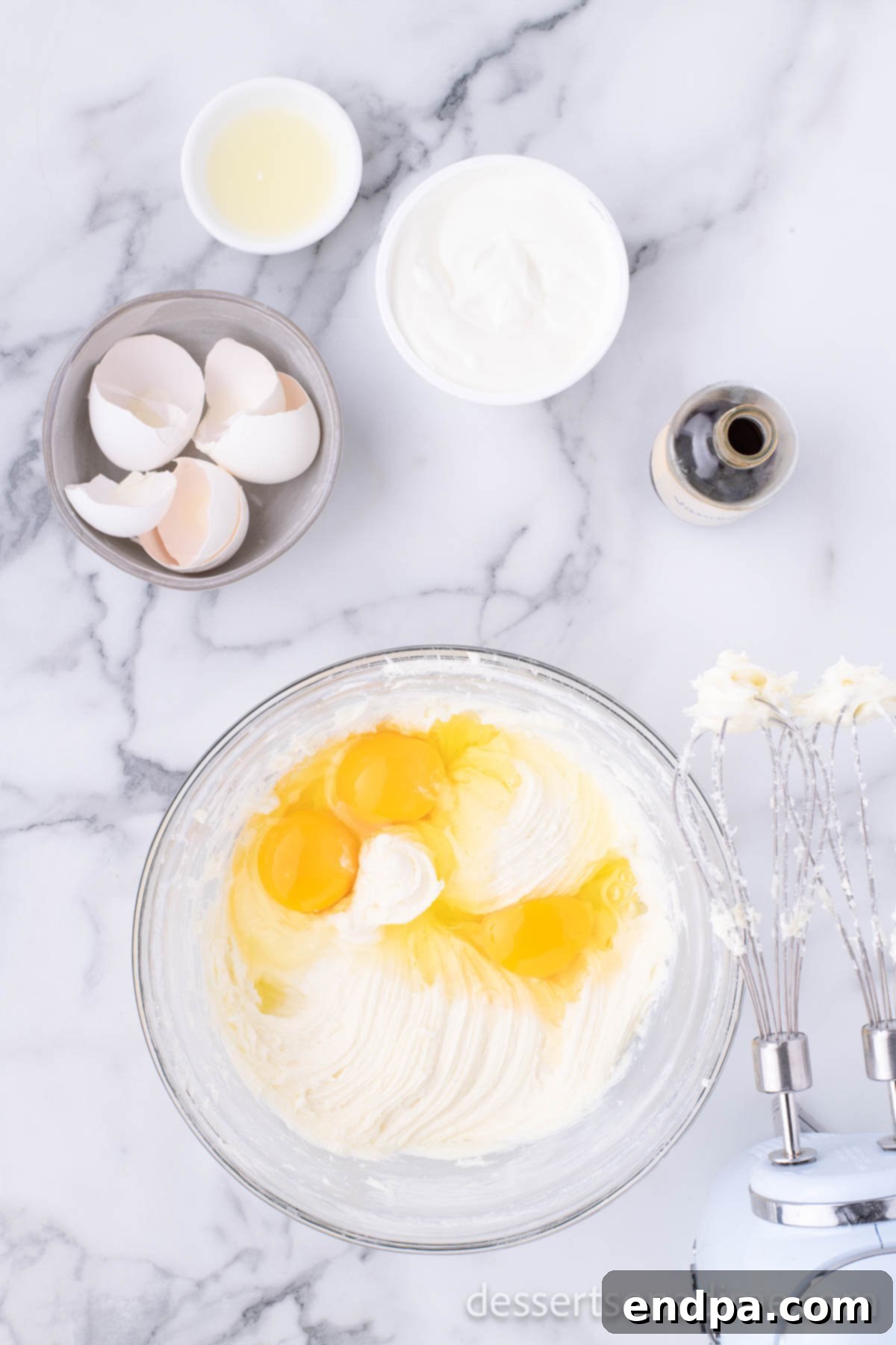 Creamy Cheesecake Delights 7 Eggs being added one at a time to the cream cheese mixture in a mixing bowl.