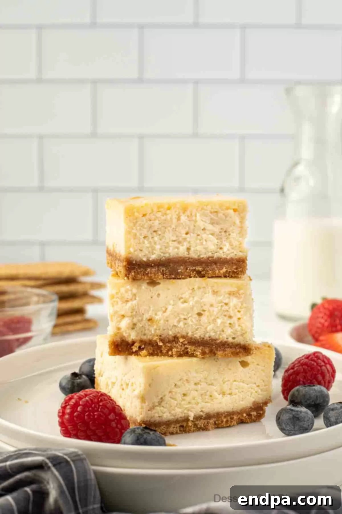 Creamy Cheesecake Delights 10 Cheesecake bars arranged in a stack on a plate, garnished with fresh berries and mint leaves.