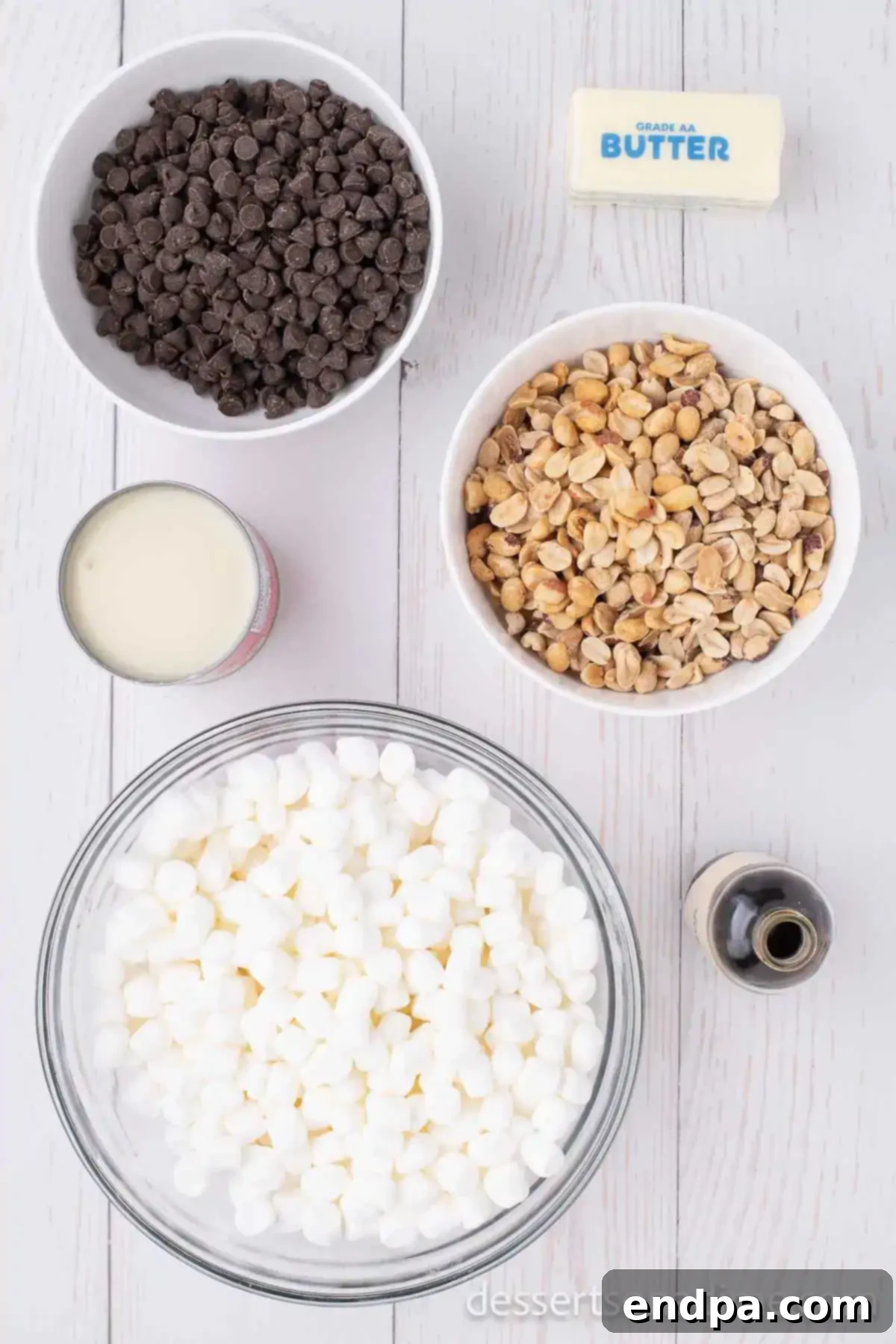 Decadent Rocky Road Dream 3 Ingredients for Rocky Road Candy recipe: a bowl of semi-sweet chocolate chips, a stick of butter, a can of sweetened condensed milk, a bag of dry roasted peanuts, and a bag of mini marshmallows.