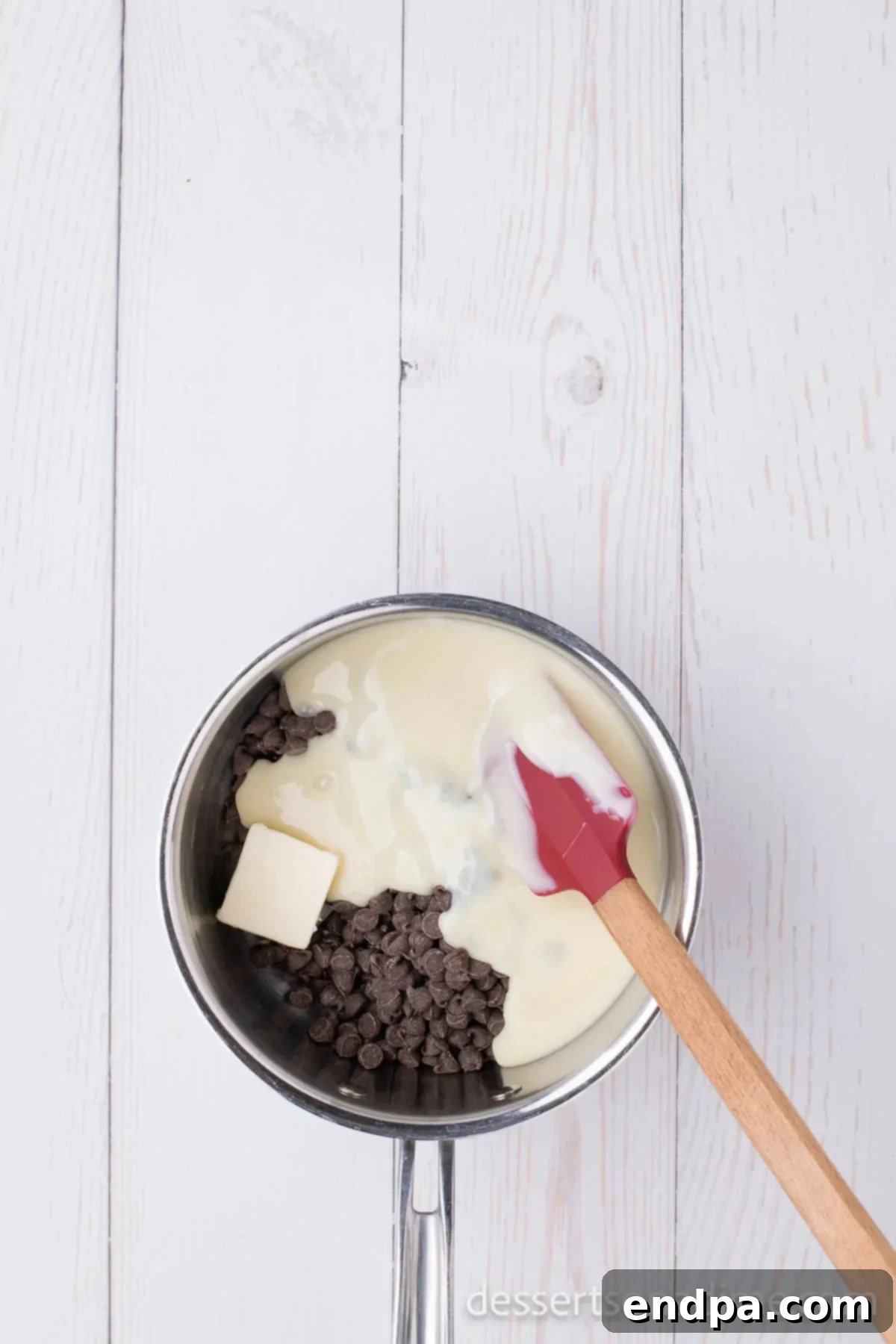 Decadent Rocky Road Dream 4 A saucepan on a stove with chocolate chips, butter, and sweetened condensed milk melting together over low heat.