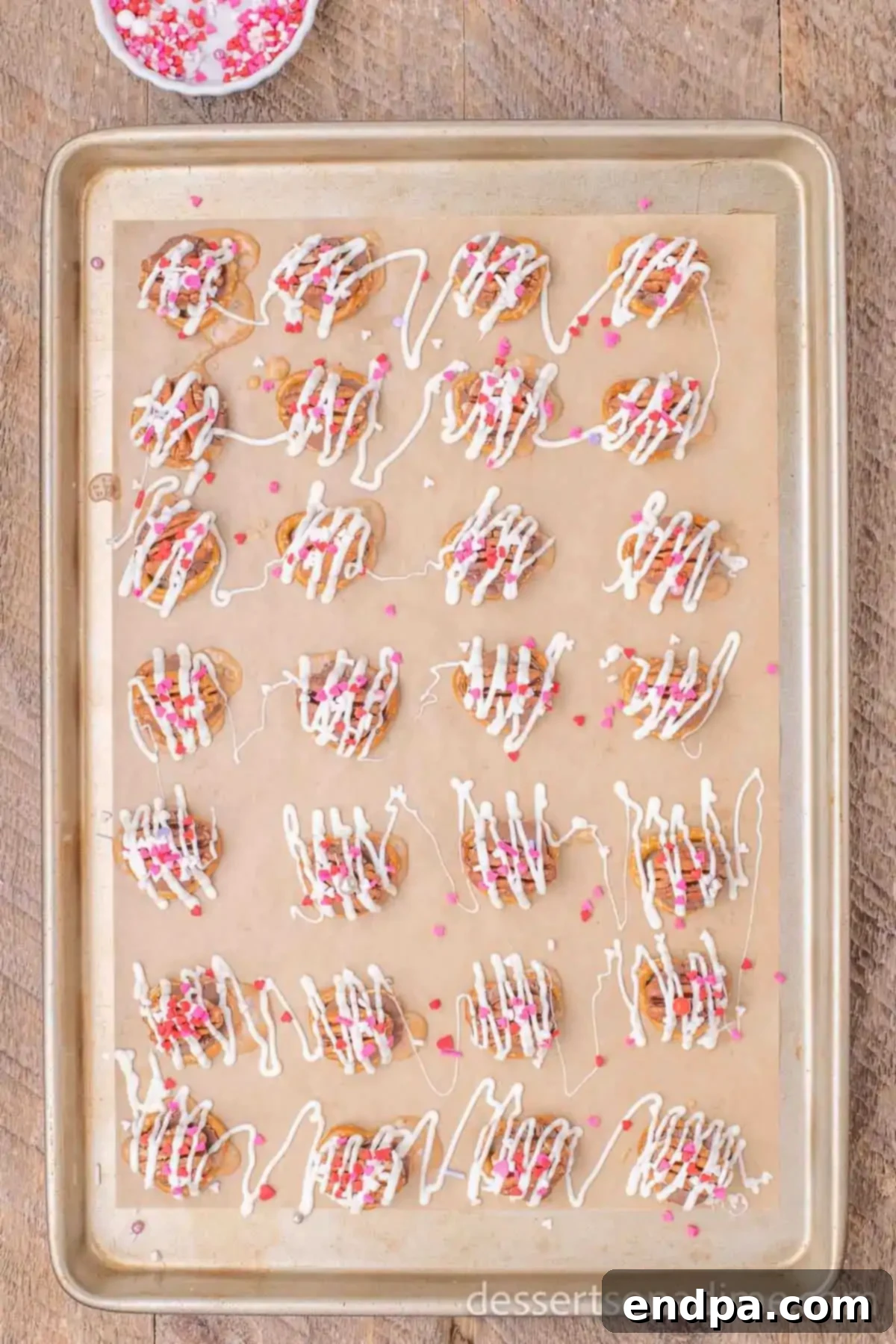 Close-up of Rolo Pretzel Turtles with colorful Valentine's Day sprinkles added on top, ready for cooling.