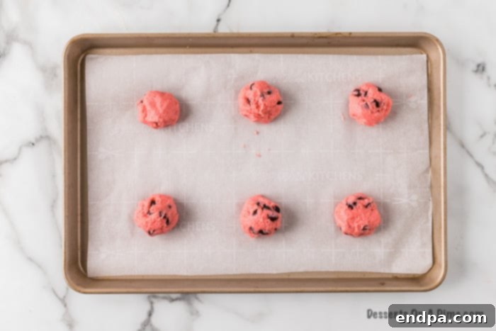 Uniform cookie dough balls neatly placed on a baking sheet, ready for the next step.