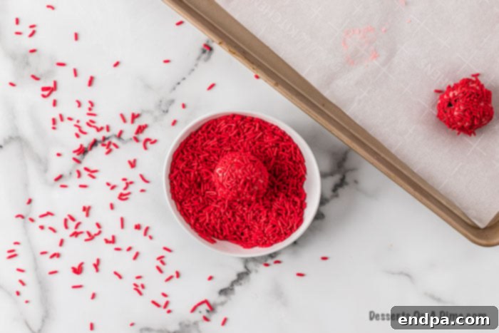 Cookie dough balls beautifully rolled in vibrant red sprinkles, adding a festive touch.