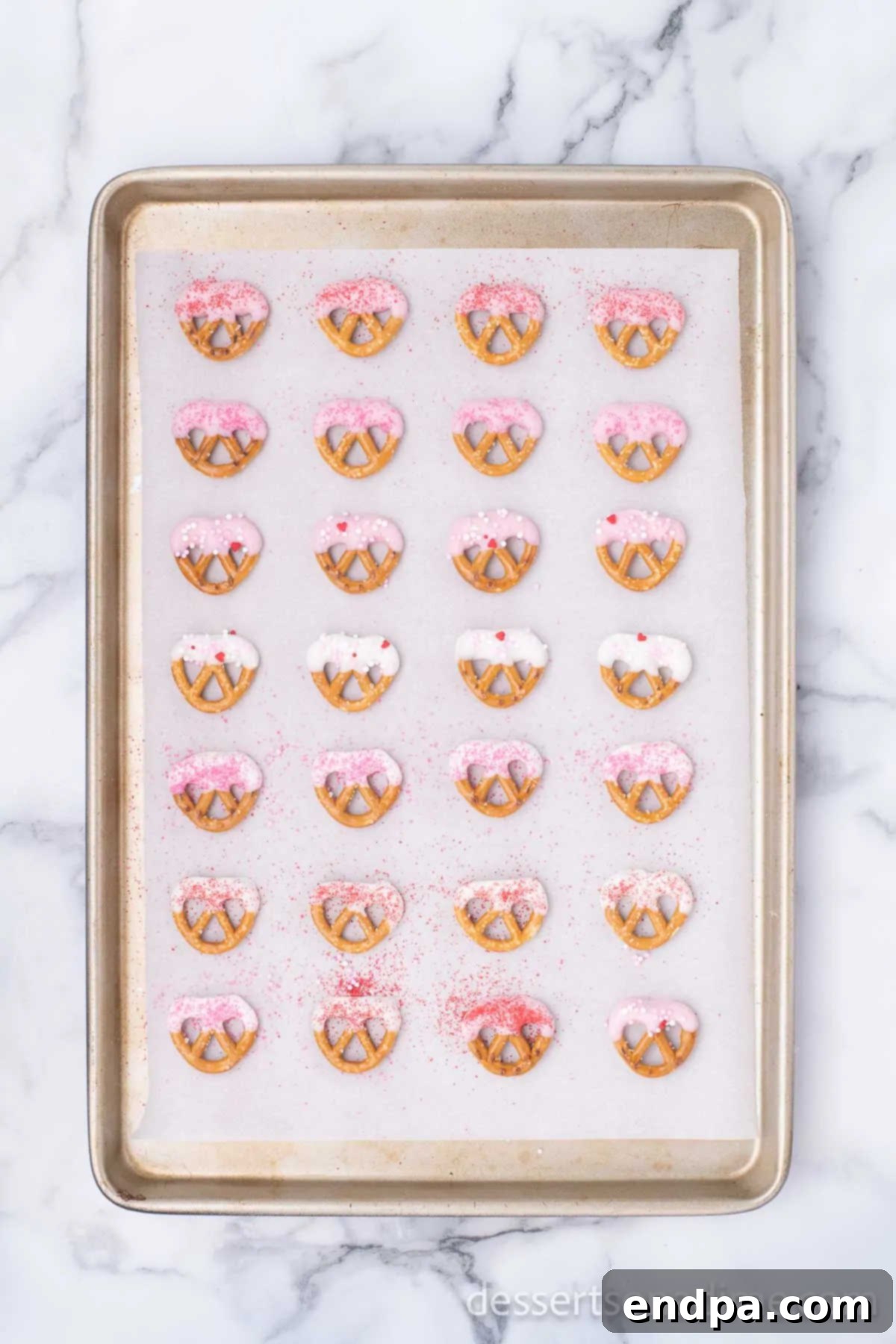 Sweet and Salty Valentine Pretzel Delights 5 Pretzels coated in chocolate and drying on a baking sheet.