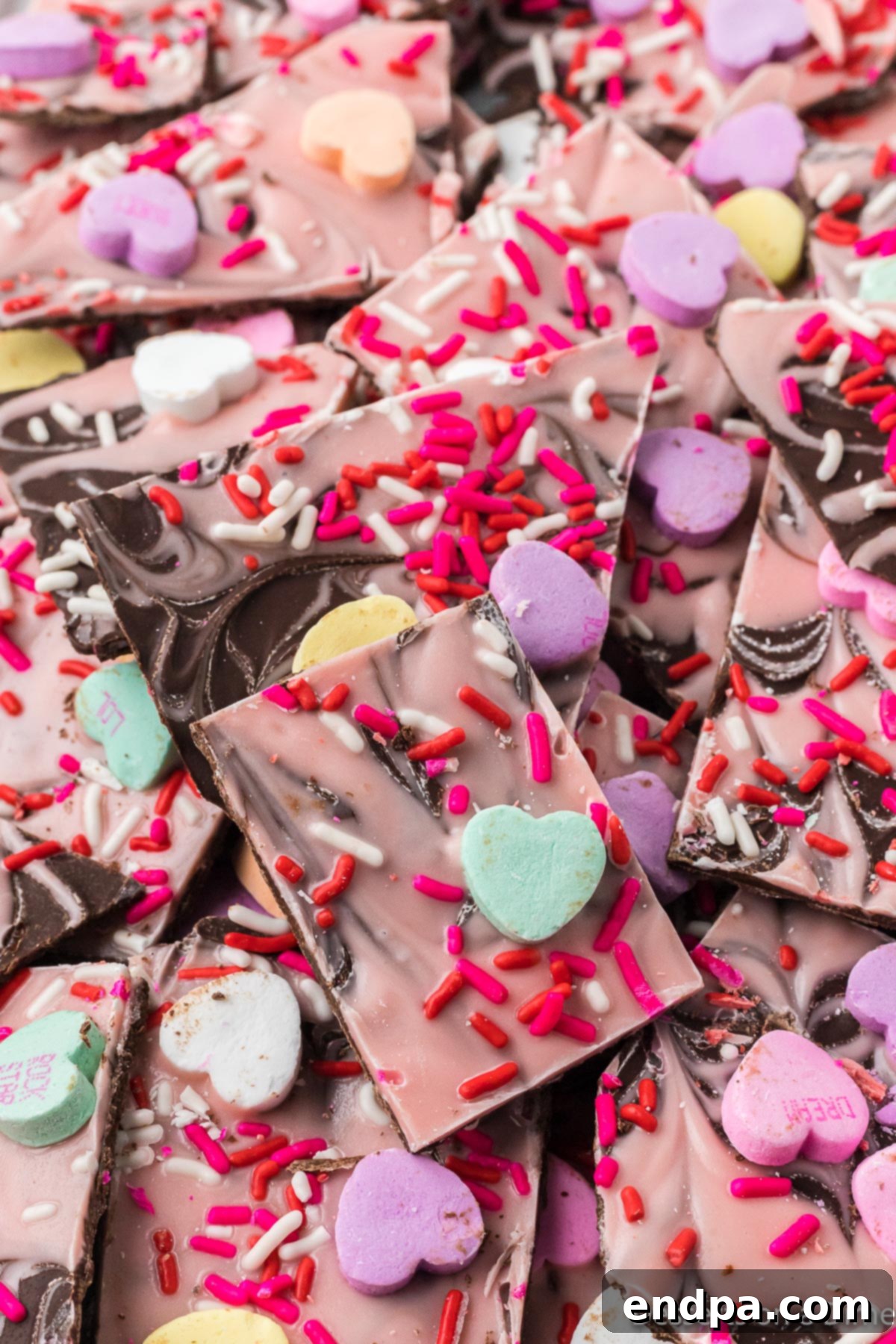 Festive Valentine Bark broken into bite-sized pieces, showcasing swirls of chocolate and colorful sprinkles.
