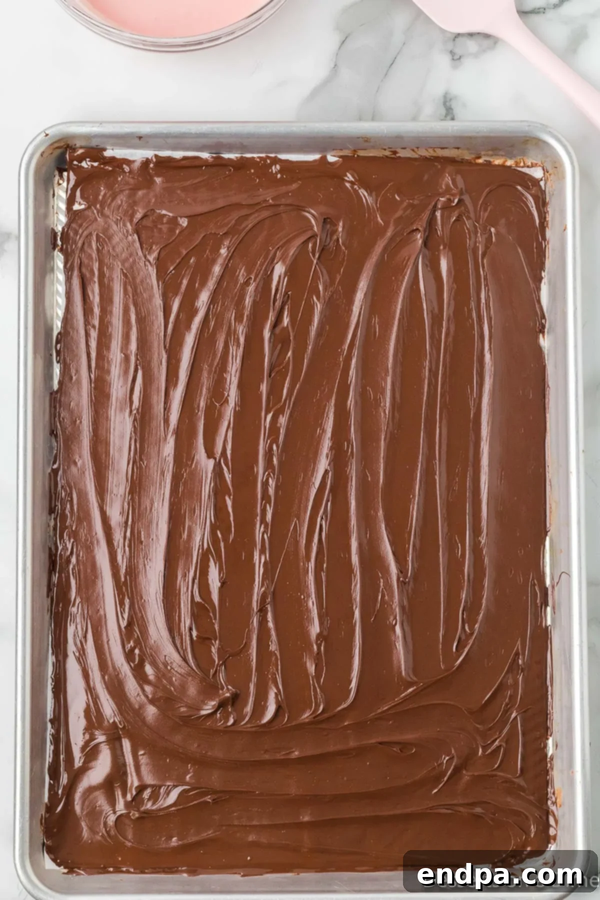 Melted chocolate evenly spread across a baking sheet lined with parchment paper.
