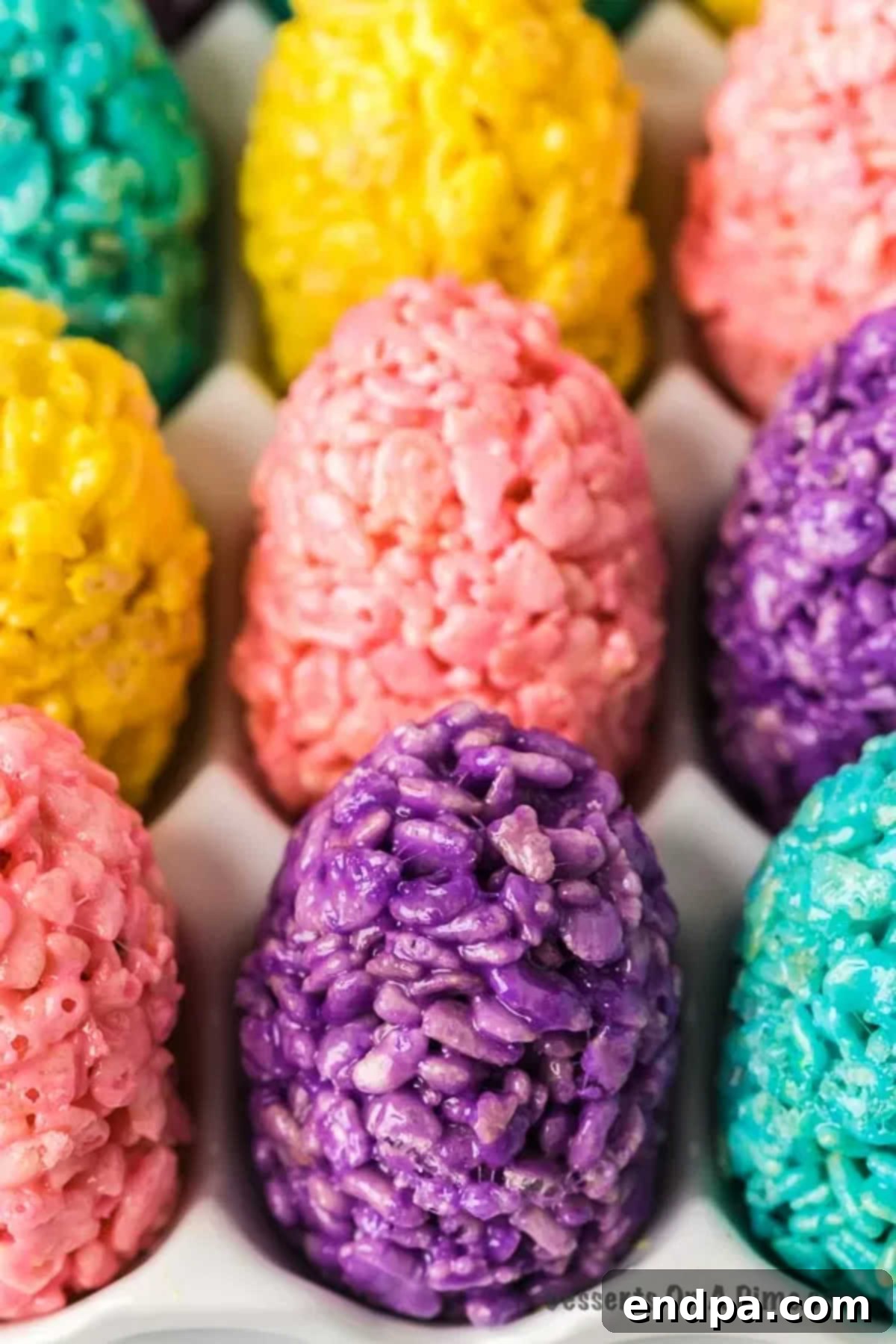 Colorful Rice Krispie Easter Egg Treats displayed in a white egg carton, ready for Easter celebrations.