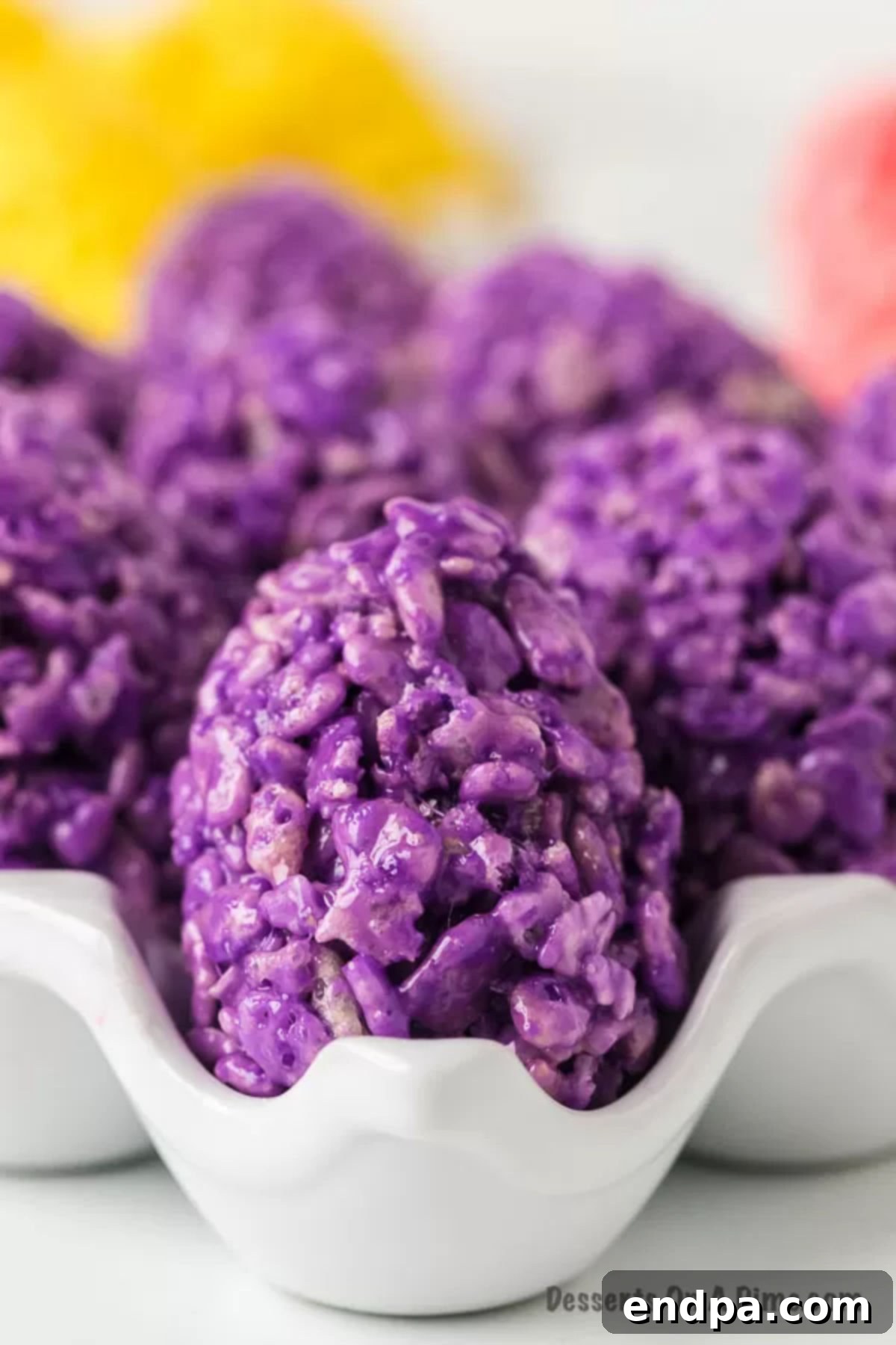 Close-up of vibrant Rice Krispie Easter Egg Treats nestled in a white egg carton, showcasing their colorful appeal.
