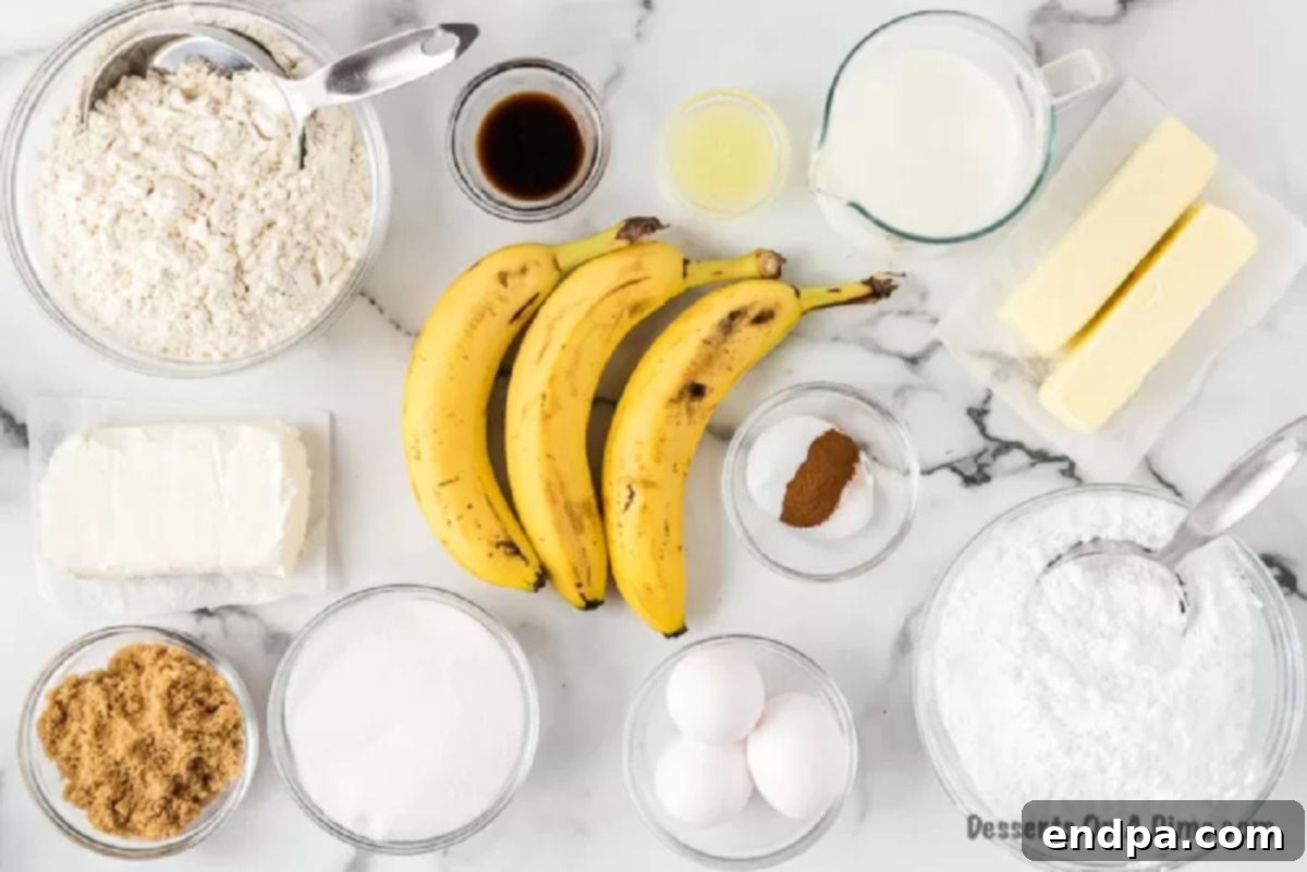 Foolproof Ultra-Moist Banana Cake 3 A flat lay photograph displaying all the fresh and pantry ingredients required for the banana cake and cream cheese frosting, including ripe bananas, flour, sugar, butter, eggs, vanilla, milk, lemon, cream cheese, and powdered sugar.