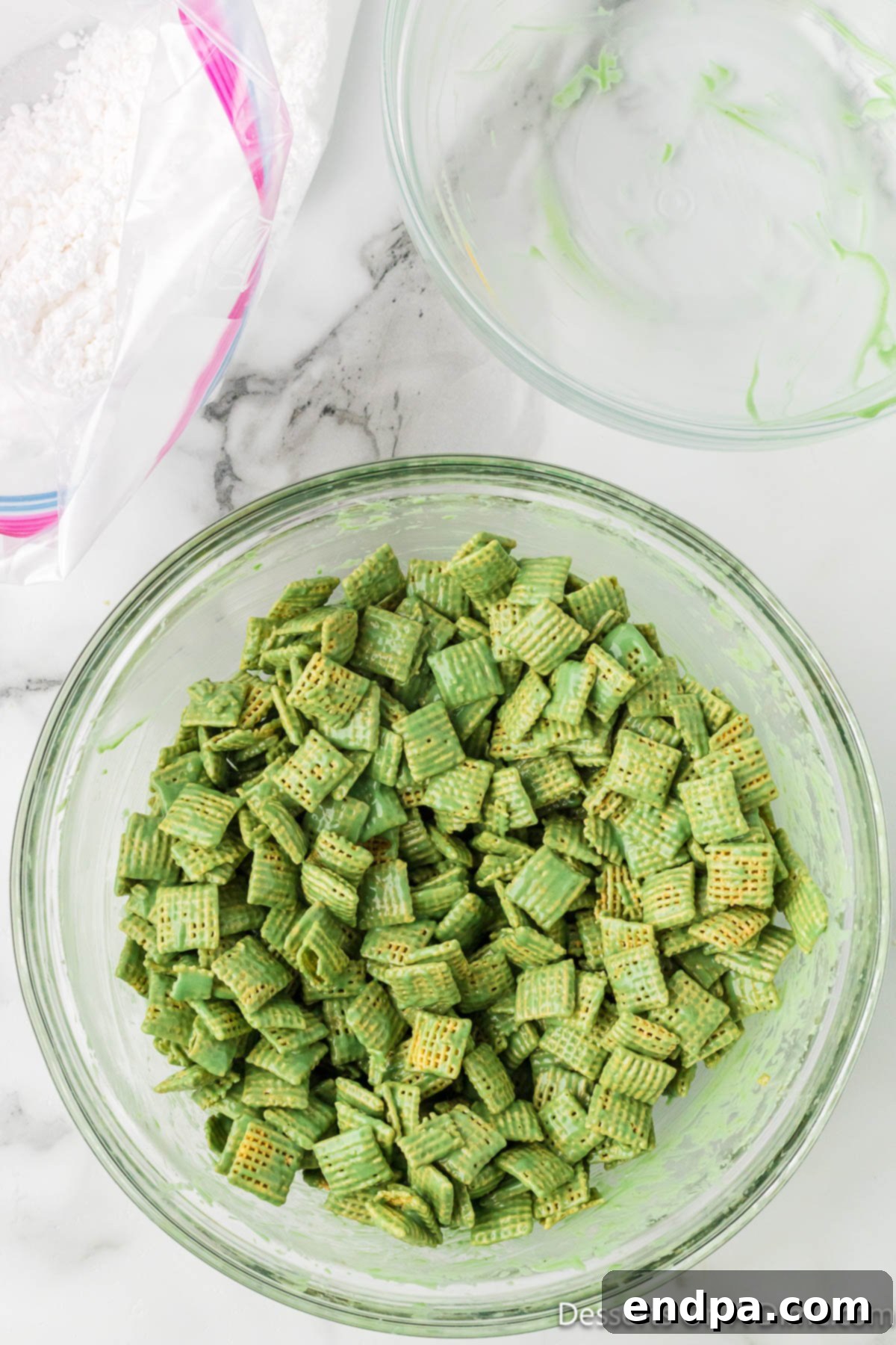 Whoville Christmas Crunch 6 Chex cereal coated evenly in the vibrant green candy and peanut butter mixture in a large mixing bowl.