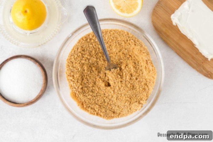 Zesty Lemon Cheesecake Bars 4 Crushed graham crackers in a bowl with melted butter, ready to be mixed for the crust.
