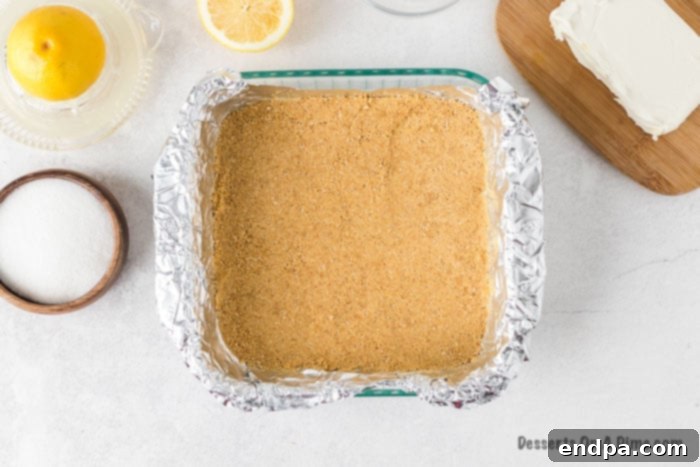 Zesty Lemon Cheesecake Bars 5 Graham cracker mixture pressed into an even layer in a prepared baking dish.