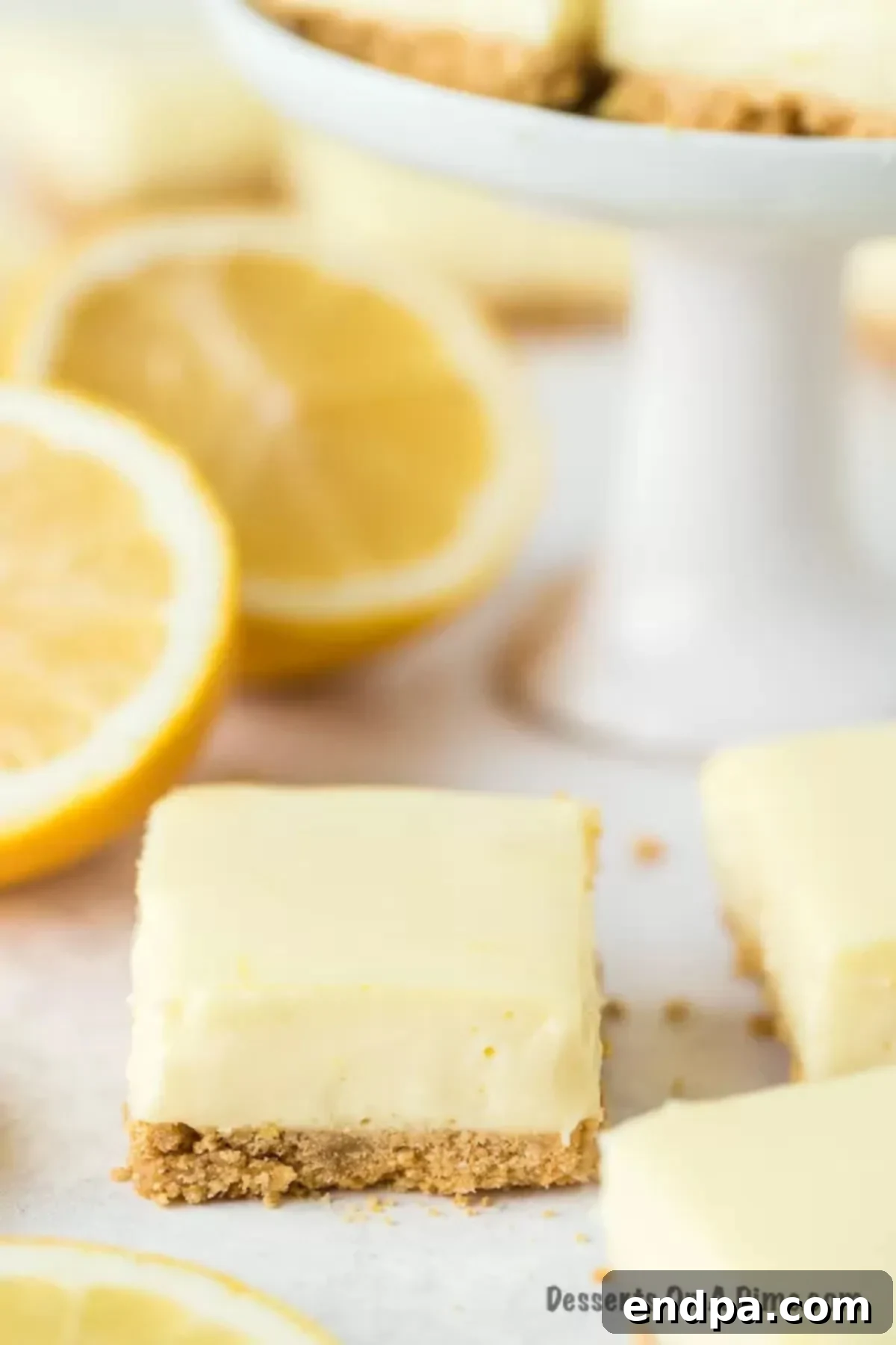 Zesty Lemon Cheesecake Bars 10 A beautifully sliced lemon bar with fresh lemons in the background, ready to be enjoyed.