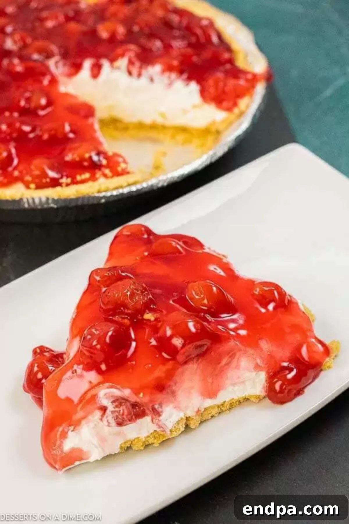 Slice of No Bake Cherry Cheesecake on a plate, showcasing its creamy texture and rich cherry topping.