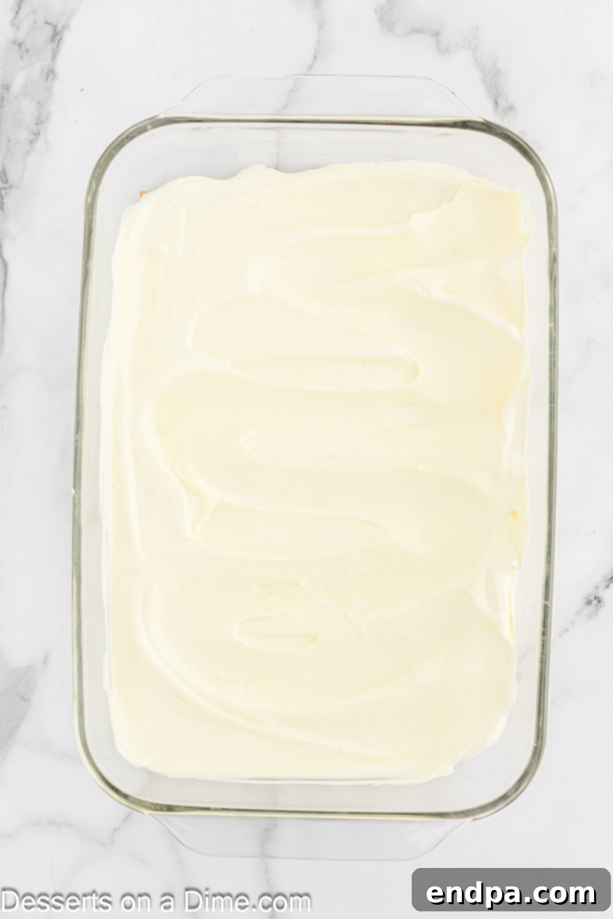 Creamy lemon pudding mixture evenly spread over a layer of graham crackers in a baking dish.