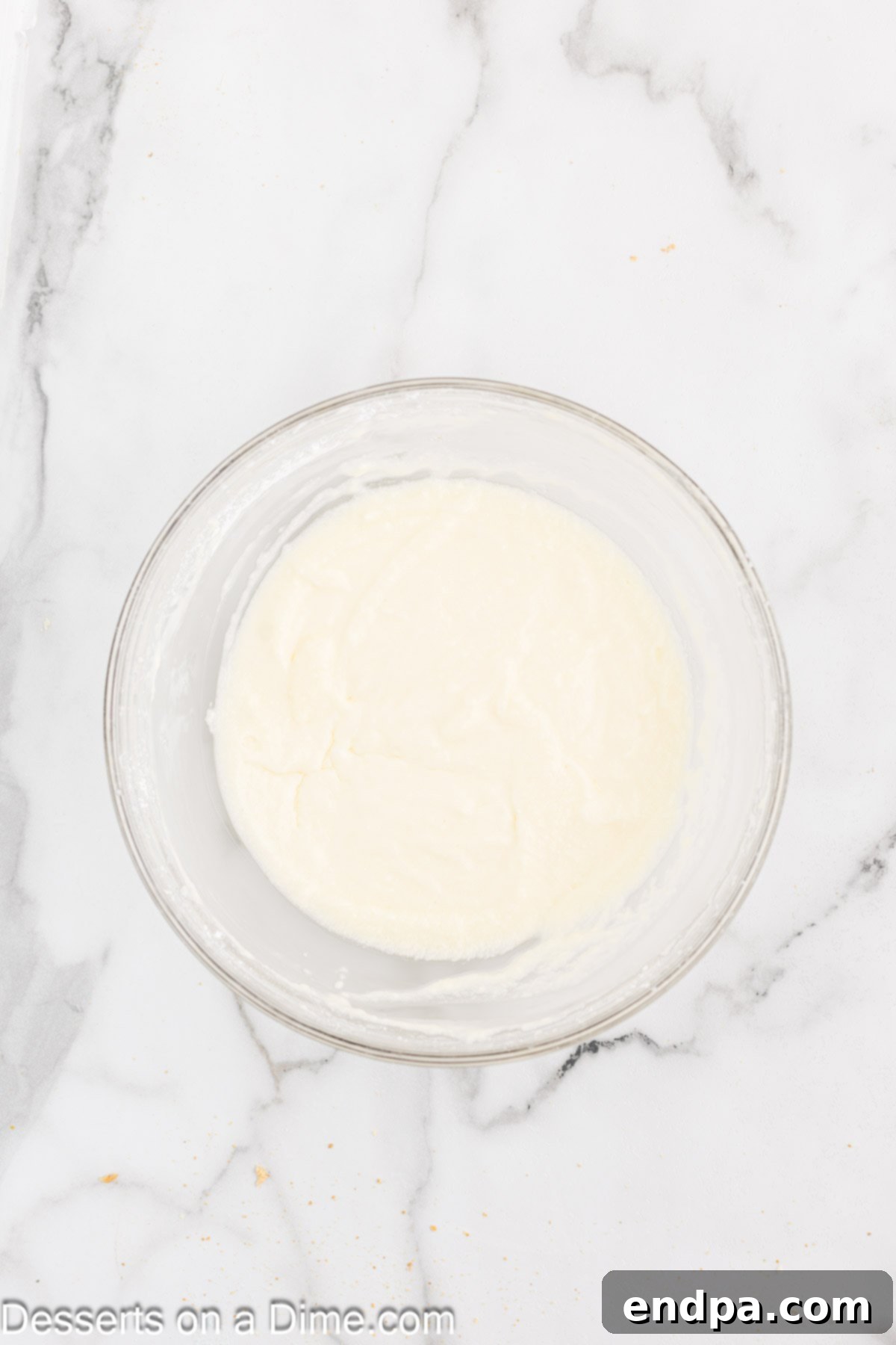 A mixing bowl containing ingredients for homemade lemon frosting being combined.