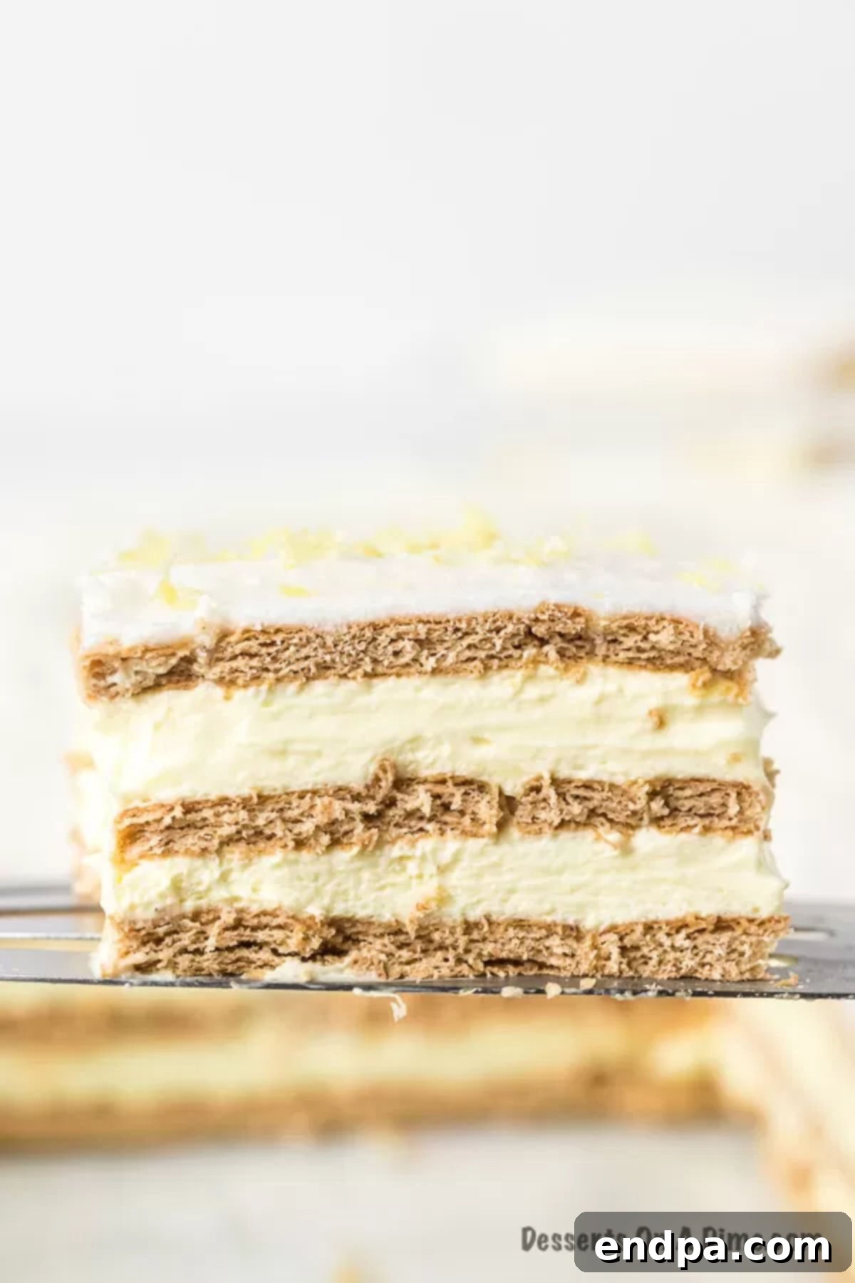 Close-up of Lemon Icebox Cake topped with vibrant lemon wedges and a dusting of zest, showcasing its delightful texture.