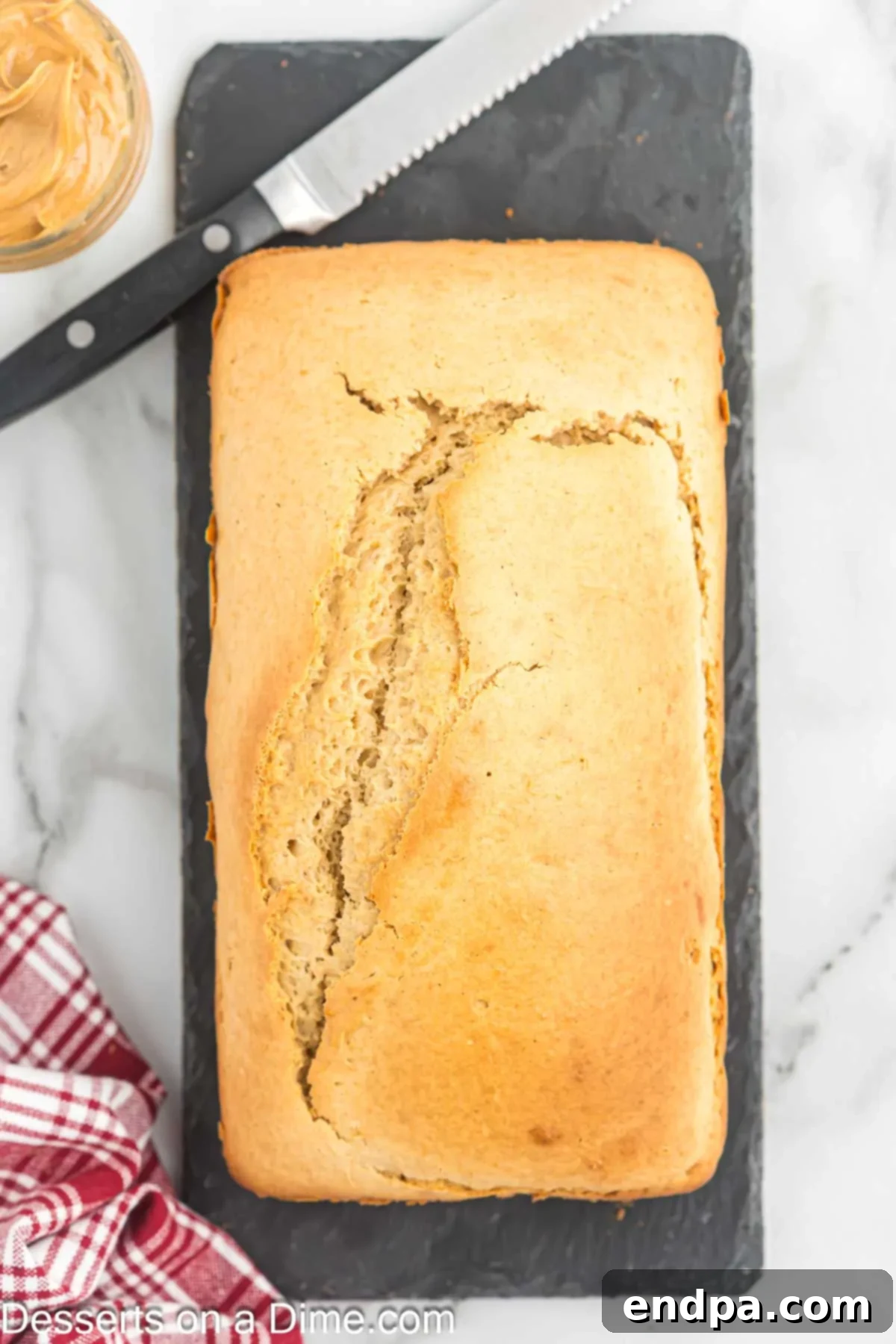A freshly baked loaf of peanut butter bread, golden brown and perfectly risen, cooling on a wire rack after being removed from the pan.