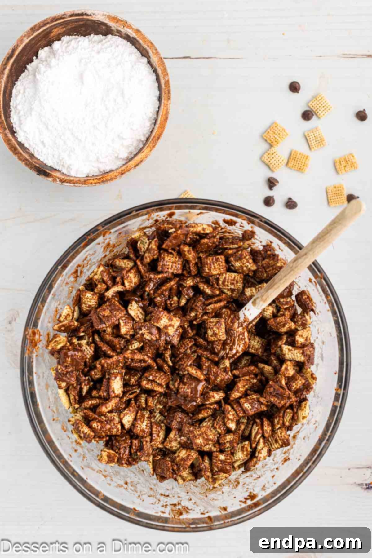 Gently stirring chocolate-coated Chex cereal with a spatula to ensure even coverage.