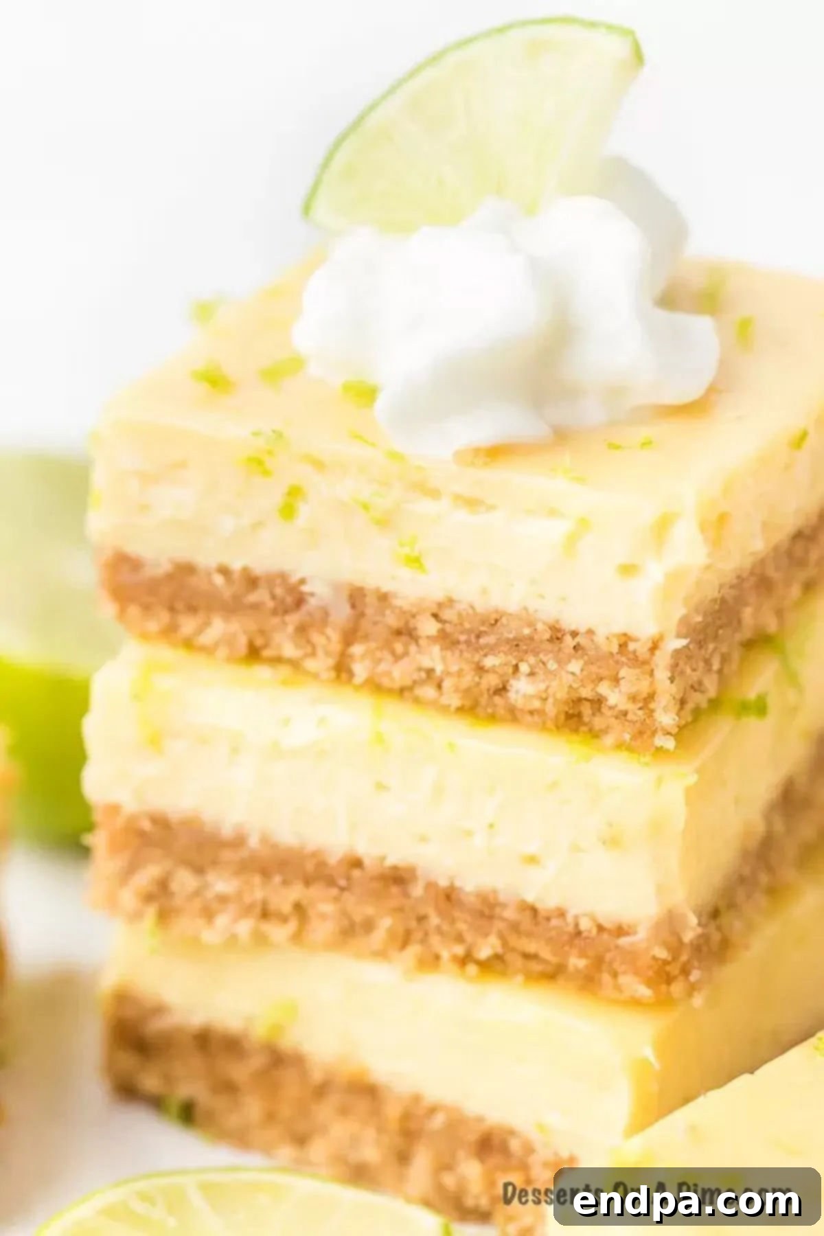 These decadent key lime bars are the perfect size for parties and more. The cream cheese filling is light and creamy with the best lime flavor. Try key lime bars easy and delicious with graham crackers crust. Key lime bars recipe is the best ever dessert and so easy. #dessertonadime #keylimebars Key Lime Bars stacked with fresh lime on top