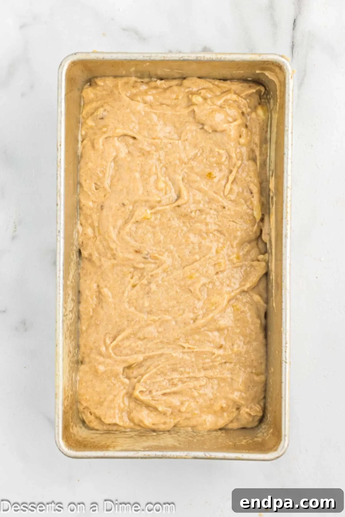 The smooth banana bread batter poured into a prepared 9x5 inch loaf pan, ready for baking.