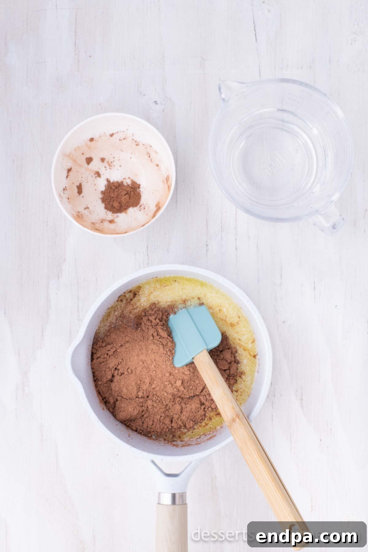 Classic Texas Chocolate Sheet Cake 3 Saucepan with butter and cocoa powder melting together on the stovetop.