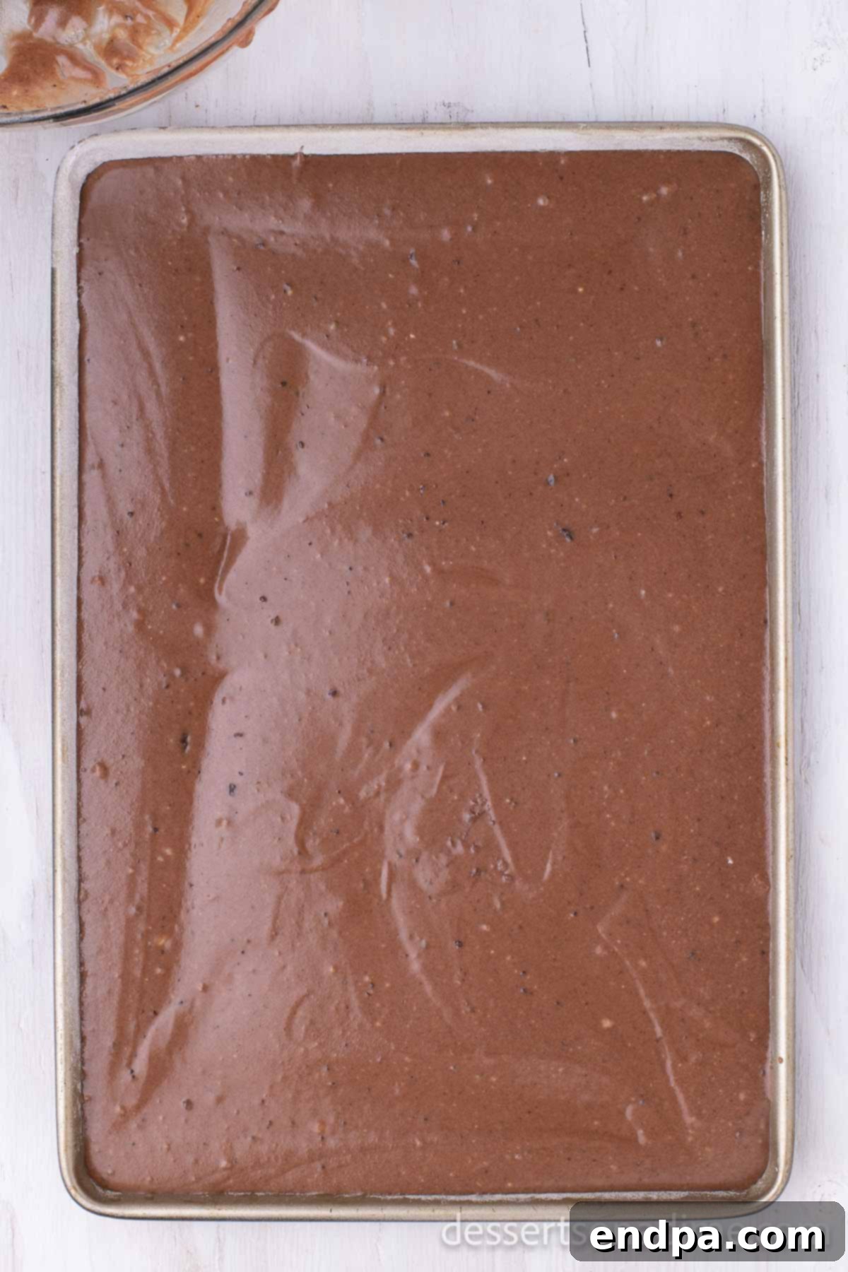 Classic Texas Chocolate Sheet Cake 5 Chocolate cake batter spread evenly into a prepared sheet pan, ready for baking.