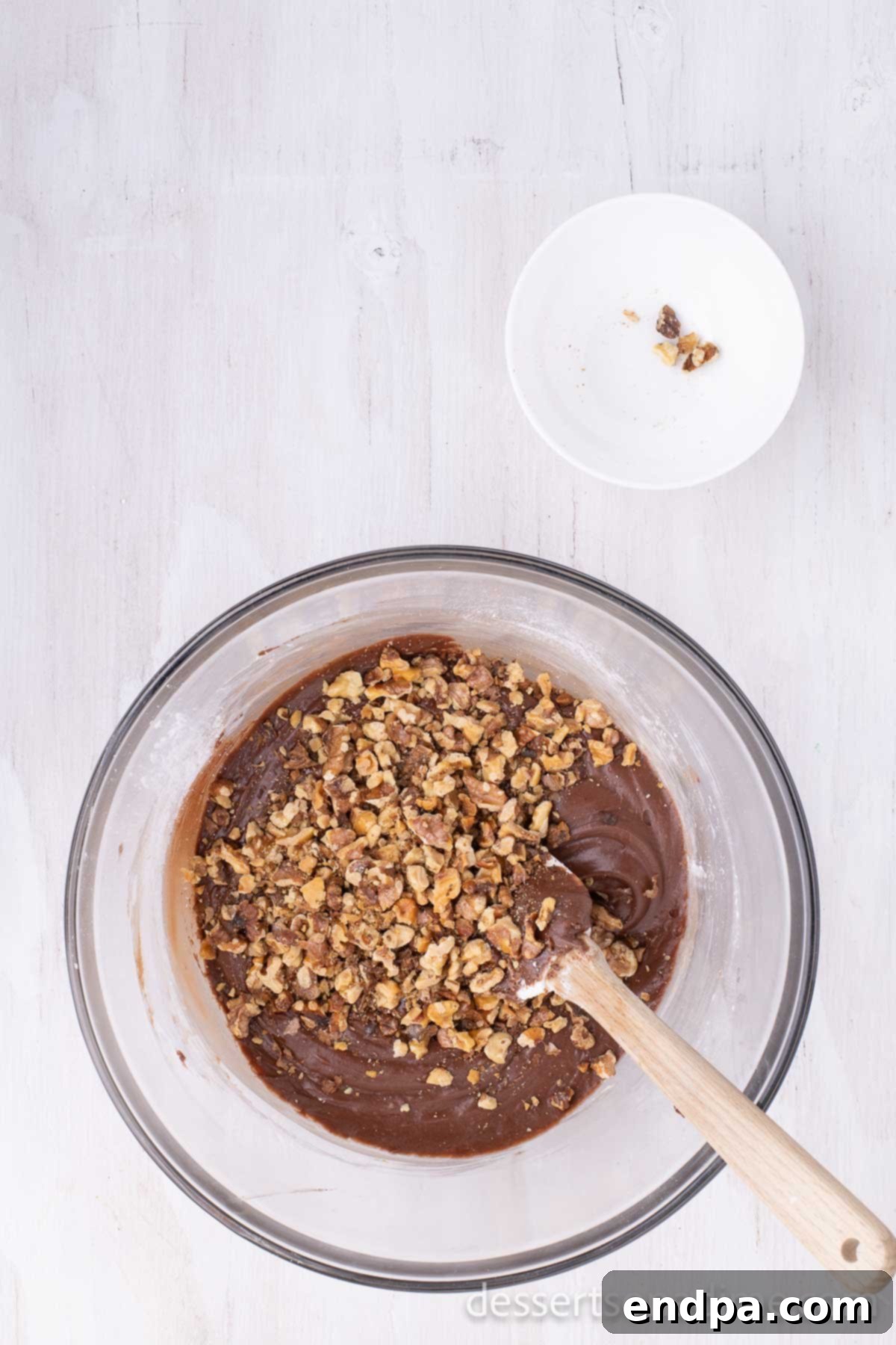 Classic Texas Chocolate Sheet Cake 7 Chopped walnuts being folded into the warm chocolate frosting mixture in a saucepan.