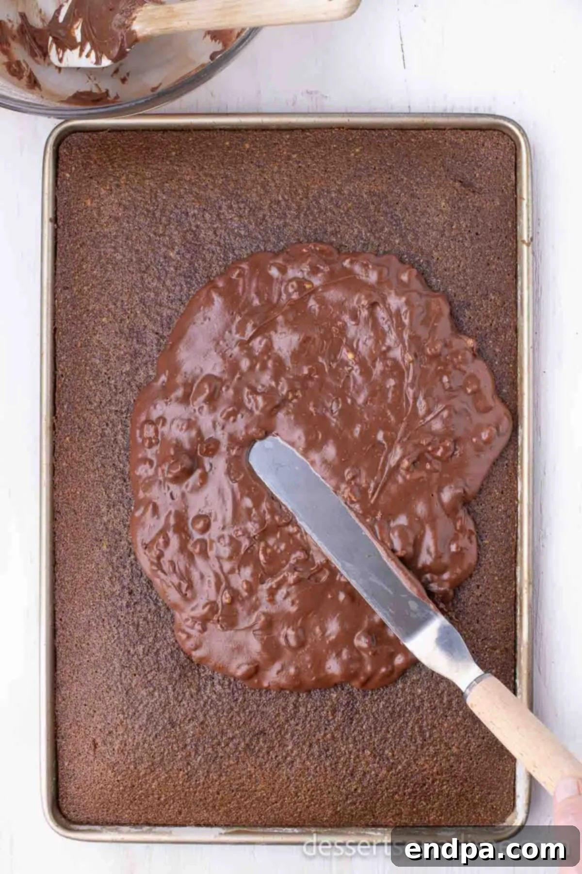 Classic Texas Chocolate Sheet Cake 8 Warm chocolate frosting being spread evenly over the still-warm Texas Sheet Cake.