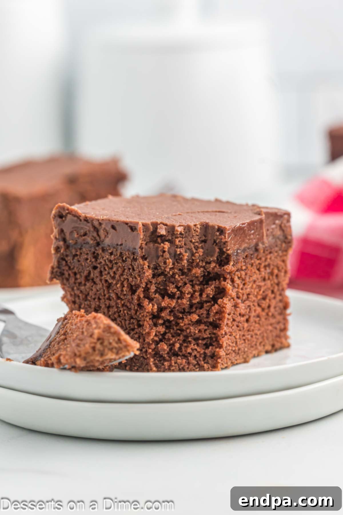 Effortless Decadent Chocolate Cake 2 A perfectly sliced piece of moist chocolate cake on a white plate, showcasing its rich texture and decadent frosting.