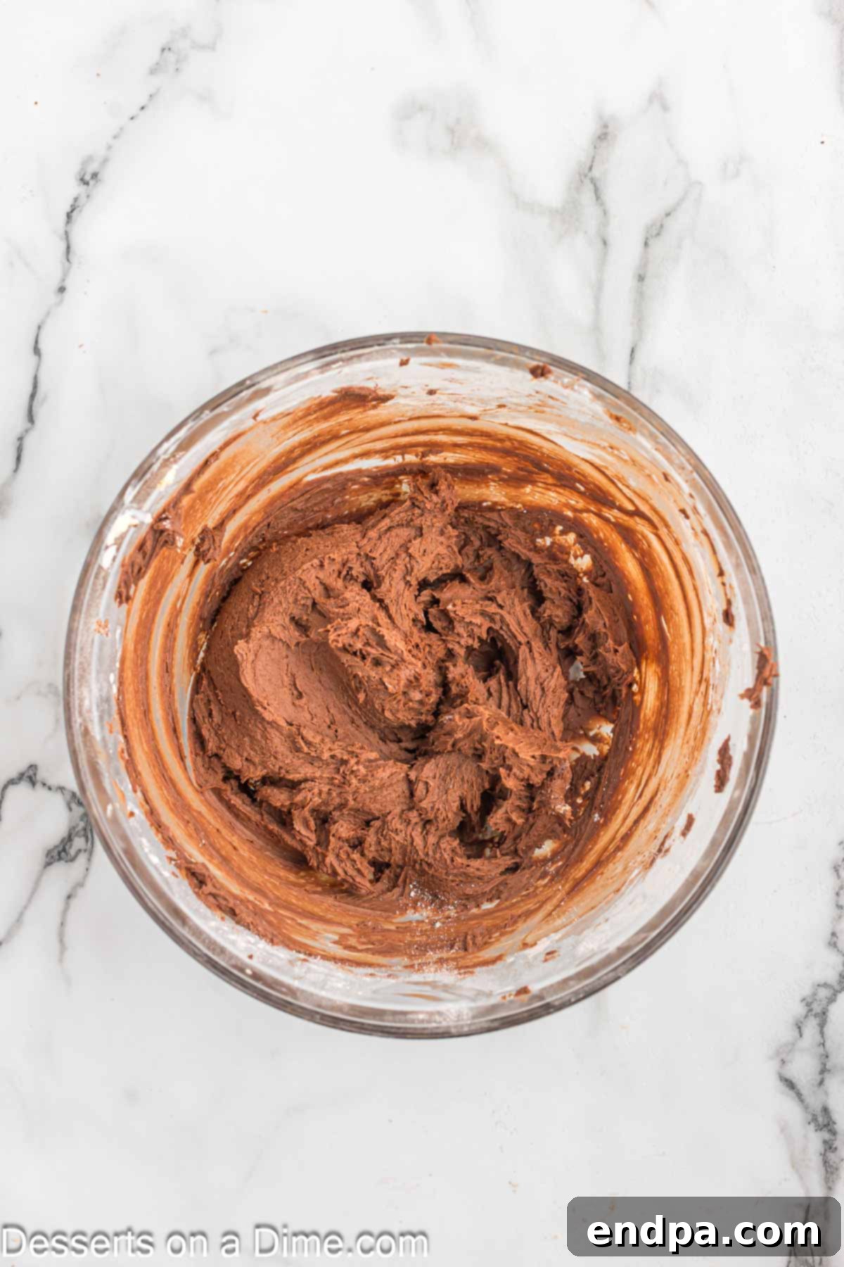 Effortless Decadent Chocolate Cake 8 Cocoa powder, heavy cream, and vanilla extract being combined with creamed butter and confectioners' sugar in a mixing bowl.