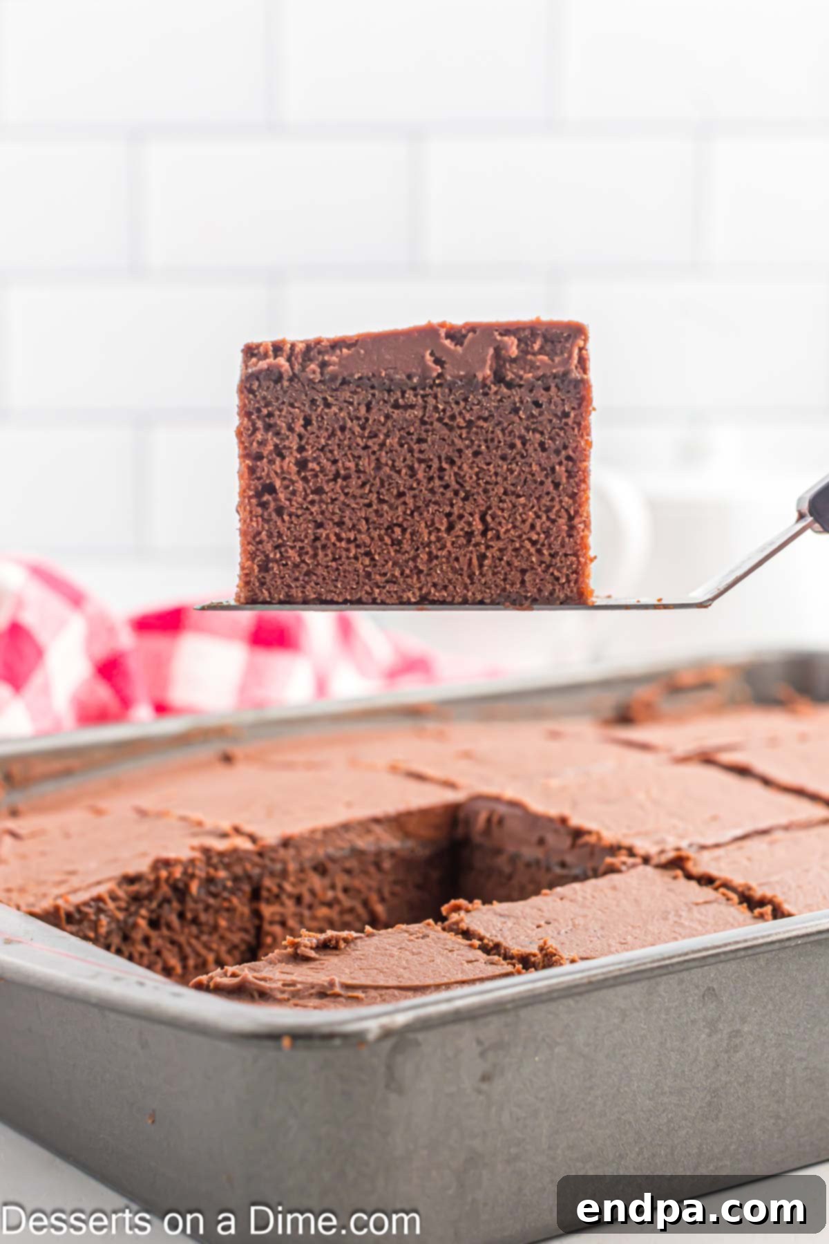 Effortless Decadent Chocolate Cake 10 A hand slicing a piece of the freshly frosted chocolate cake from the pan, ready to be served.