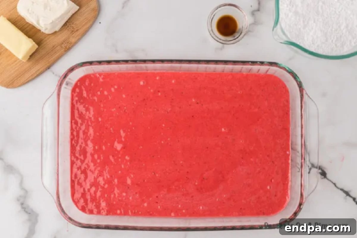 Effortless Strawberry Sheet Cake 4 The pink strawberry cake batter being poured evenly into the prepared 9x13 inch baking pan, ready for baking.