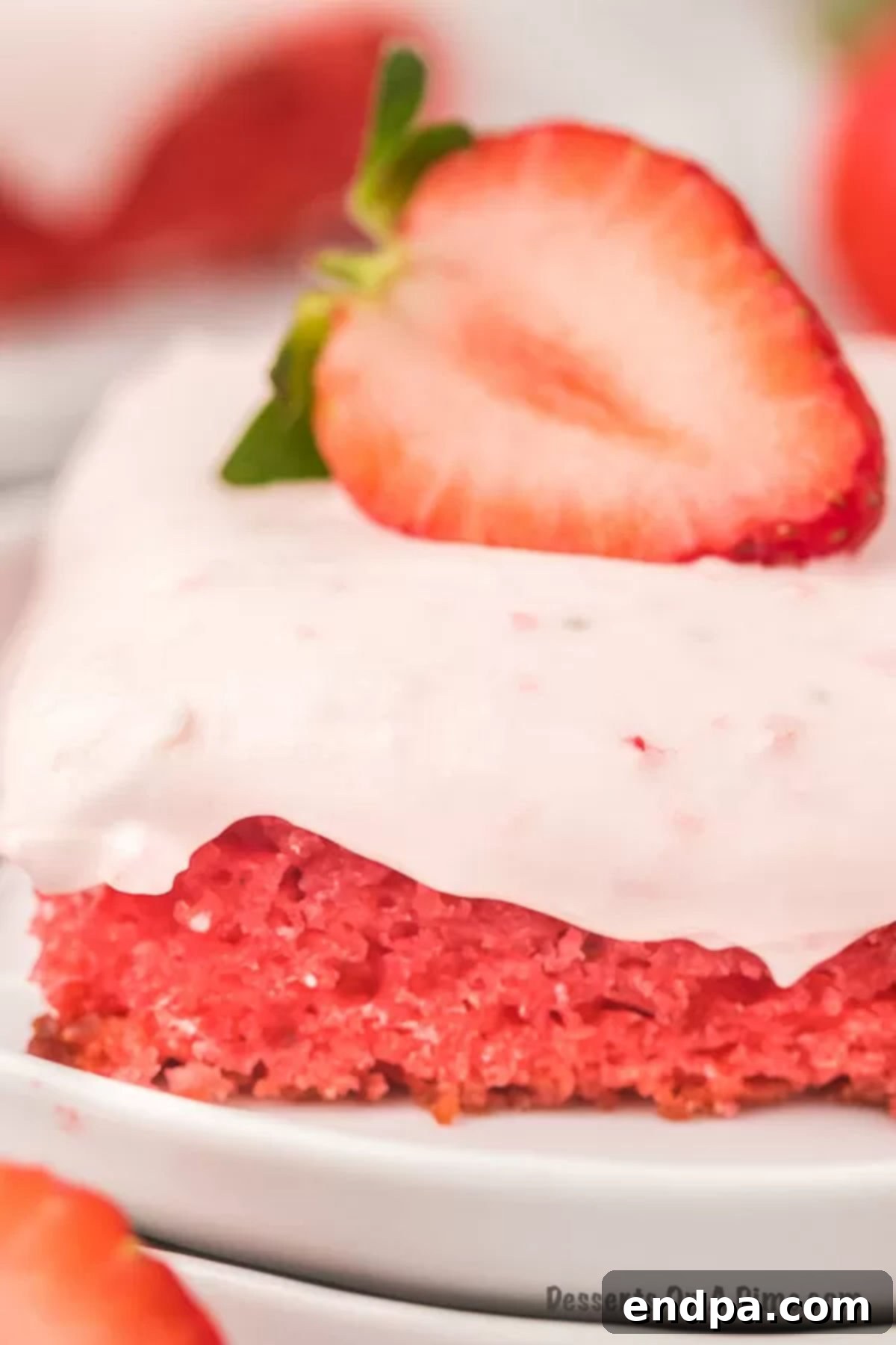 Strawberry sheet cake is so decadent with the best cream cheese frosting. No one will guess it all starts with a cake mix. An overhead view of a whole strawberry sheet cake frosted with pink cream cheese frosting and garnished with fresh strawberry slices, sitting on a serving board.