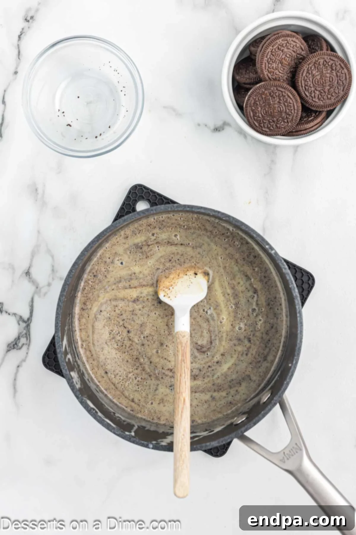 Crushed Oreo cookies being gently folded into the warm pudding mixture.