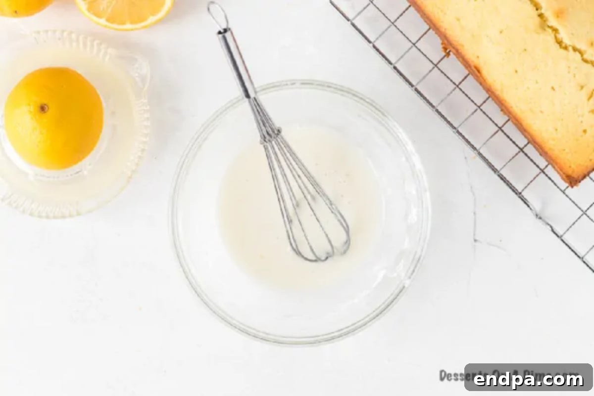 Glaze being poured evenly over the cooled lemon pound cake.
