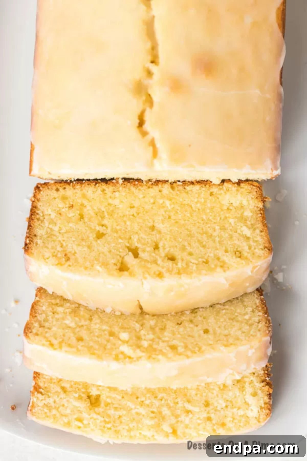 A sliced lemon loaf cake with a generous lemon glaze, revealing its moist interior.