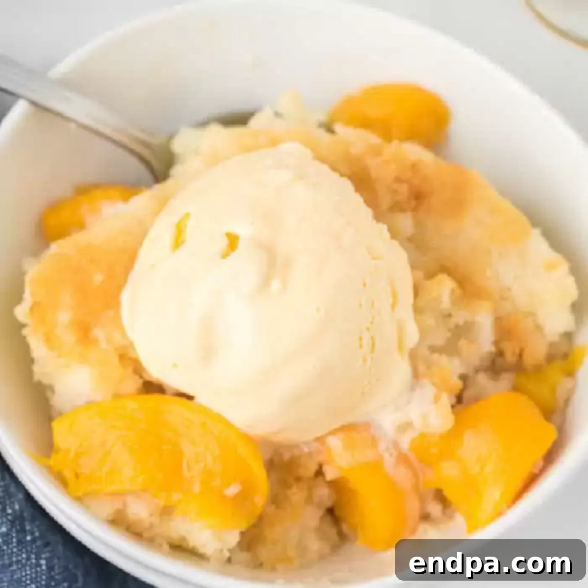 Close-up of a square baking dish filled with a golden, bubbly easy peach cobbler.