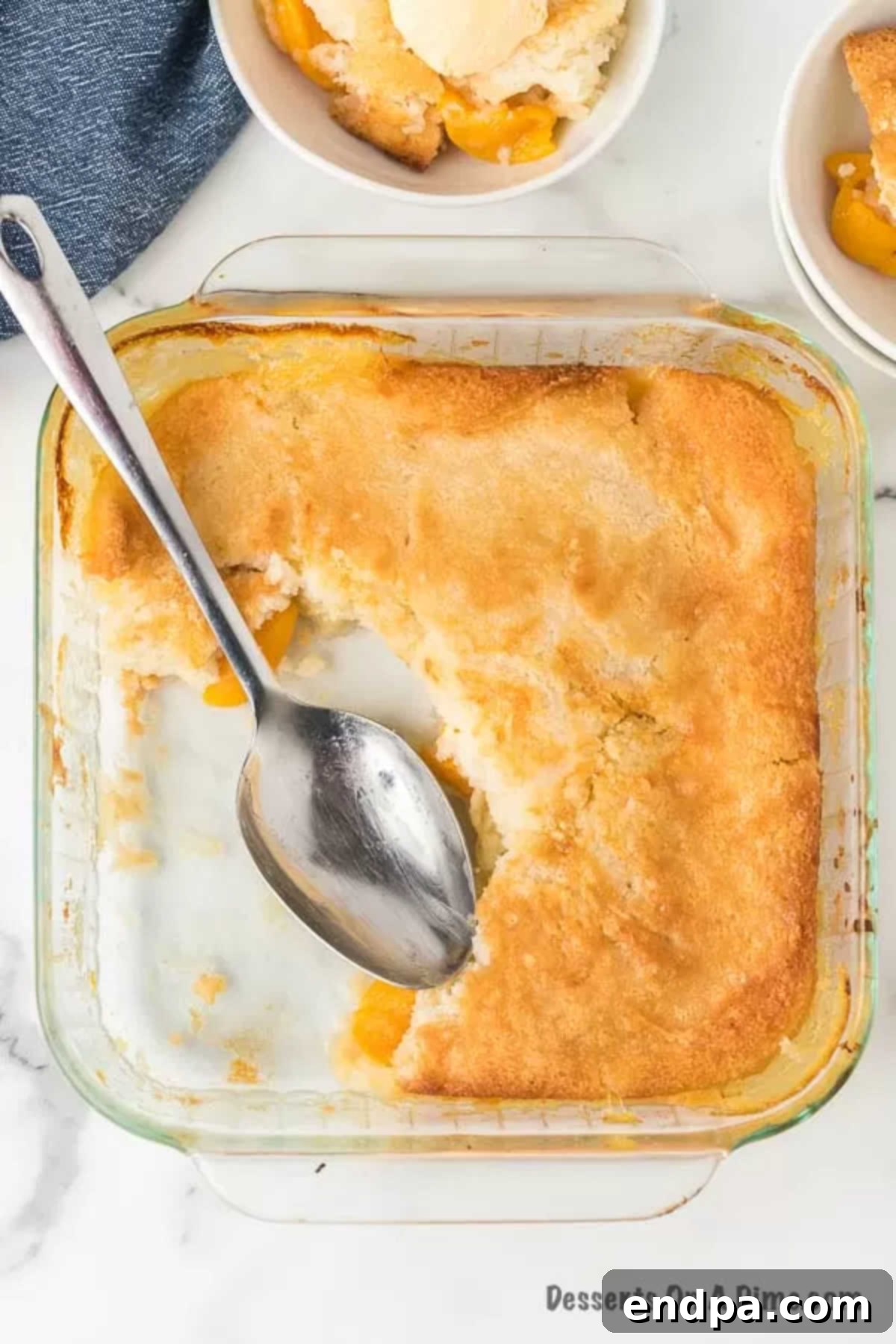 A baking dish filled with unbaked peach cobbler, showing the peach and batter layers before going into the oven.
