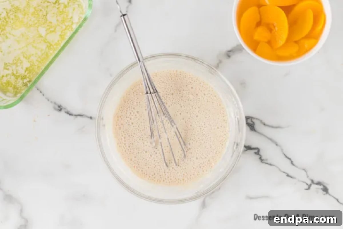 Ingredients for the cobbler topping (flour, sugar, milk, baking powder, salt) mixed together in a bowl, forming a smooth batter.
