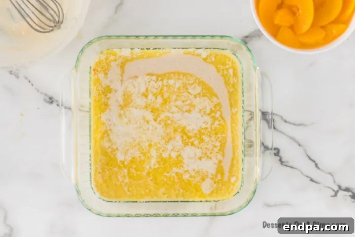 The cobbler batter being poured over the melted butter in the baking dish, creating a distinct layer.