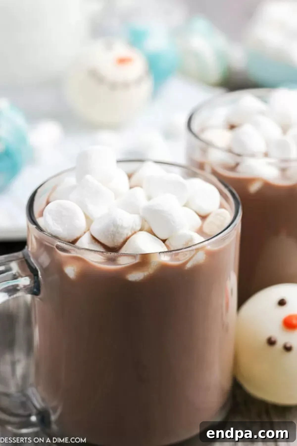 Clear mug with hot chocolate topped with marshmallows, steam rising elegantly