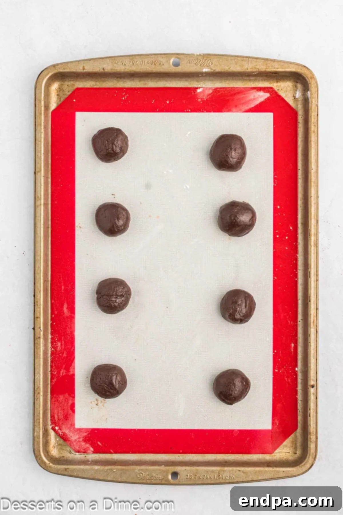 Balls of cookie dough on baking mat.